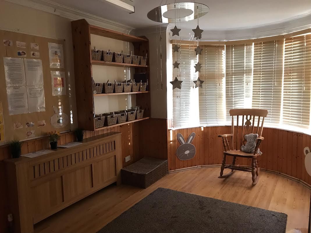 Cozy room with wooden shelves, a chair, and a large window with blinds and star decorations