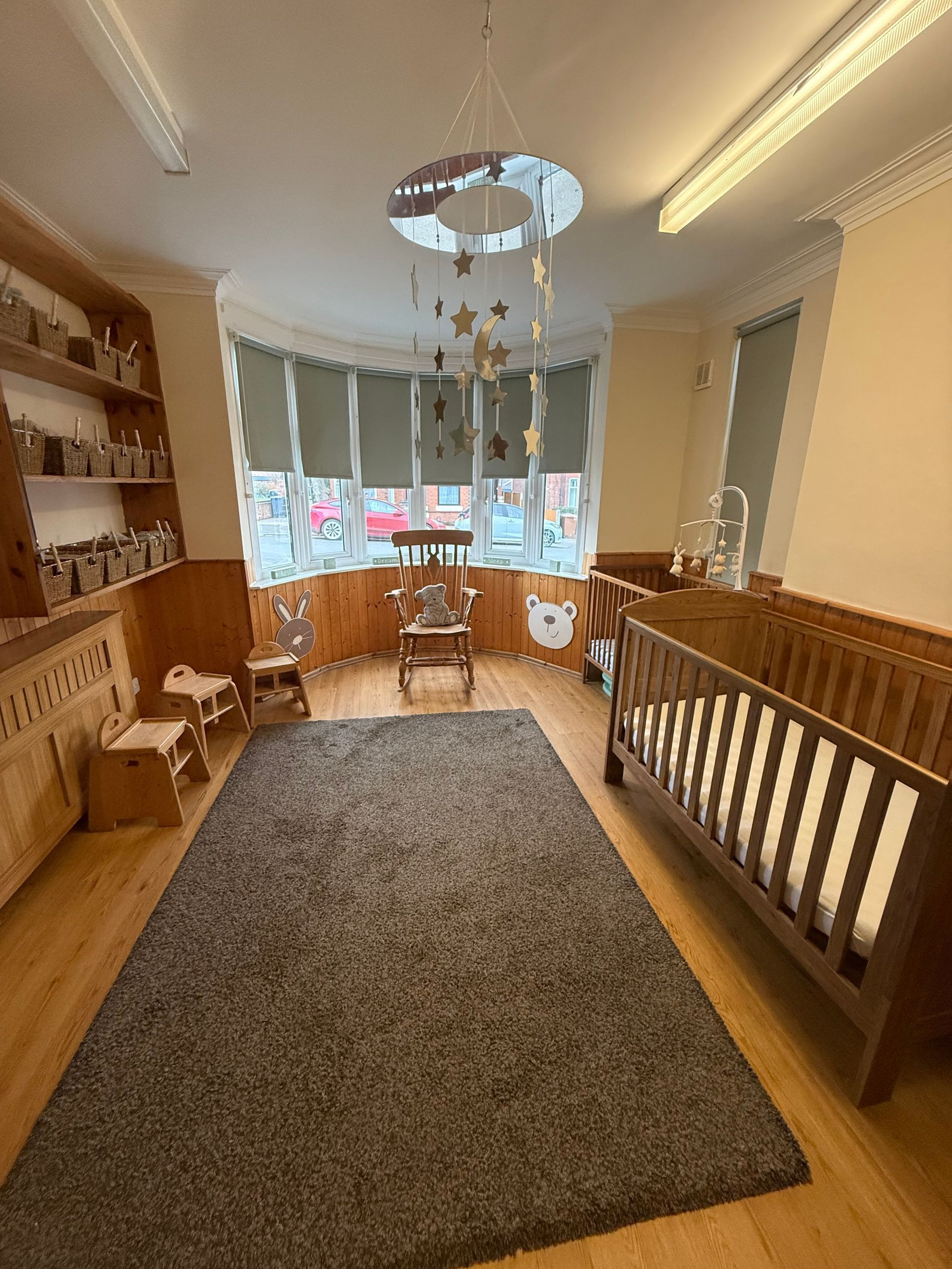 Cozy upstairs landing with wooden railings, gray rug, round table, and bay window seating area.