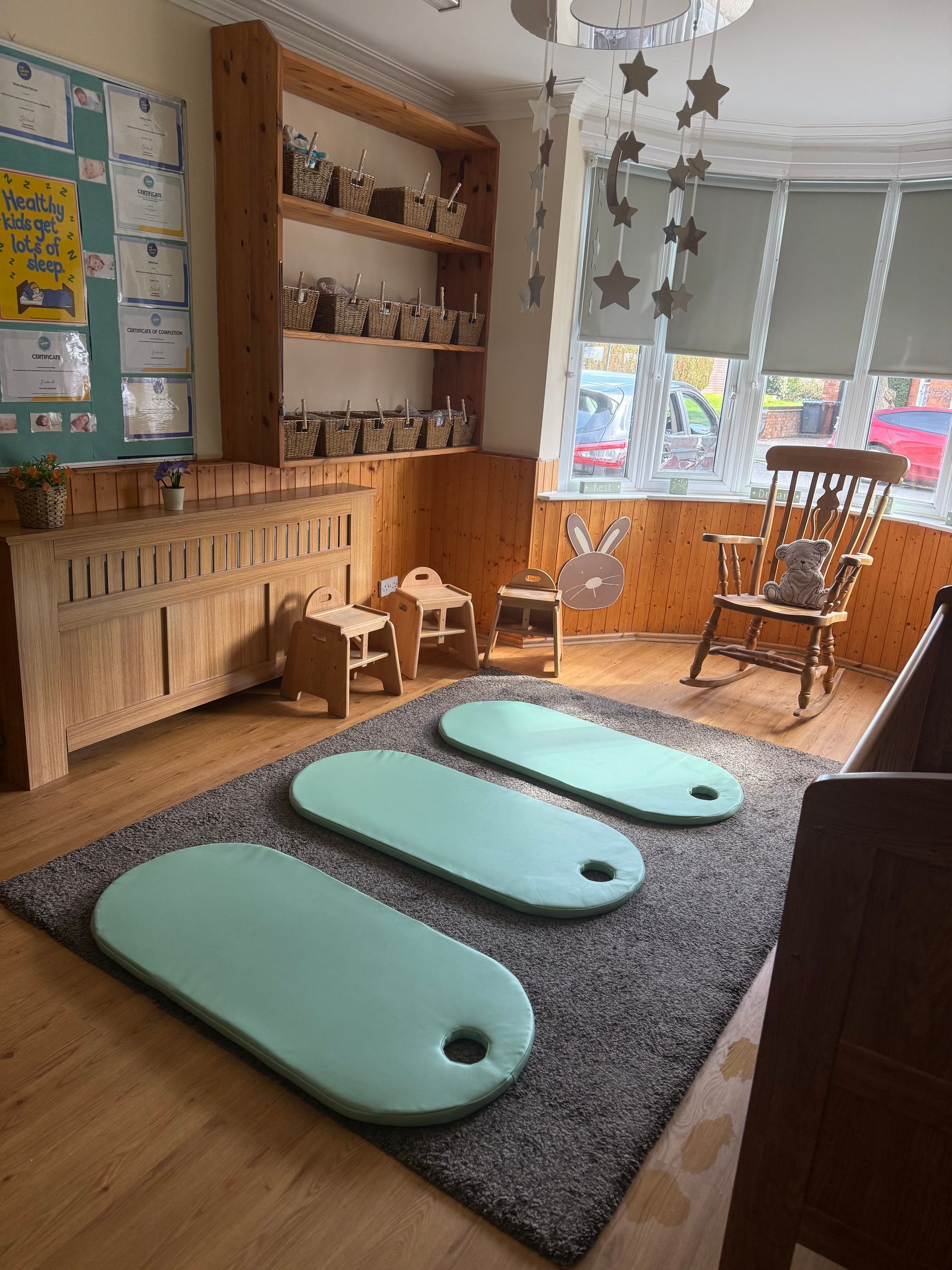 Quiet classroom reading nook with rugs, floor cushions, rocking chair, shelves, and sunlight from windows