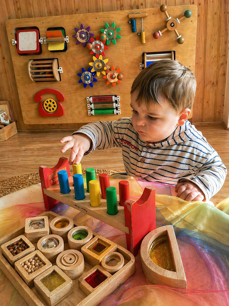 Child playing with colorful wooden toys at a table in a cozy playroom