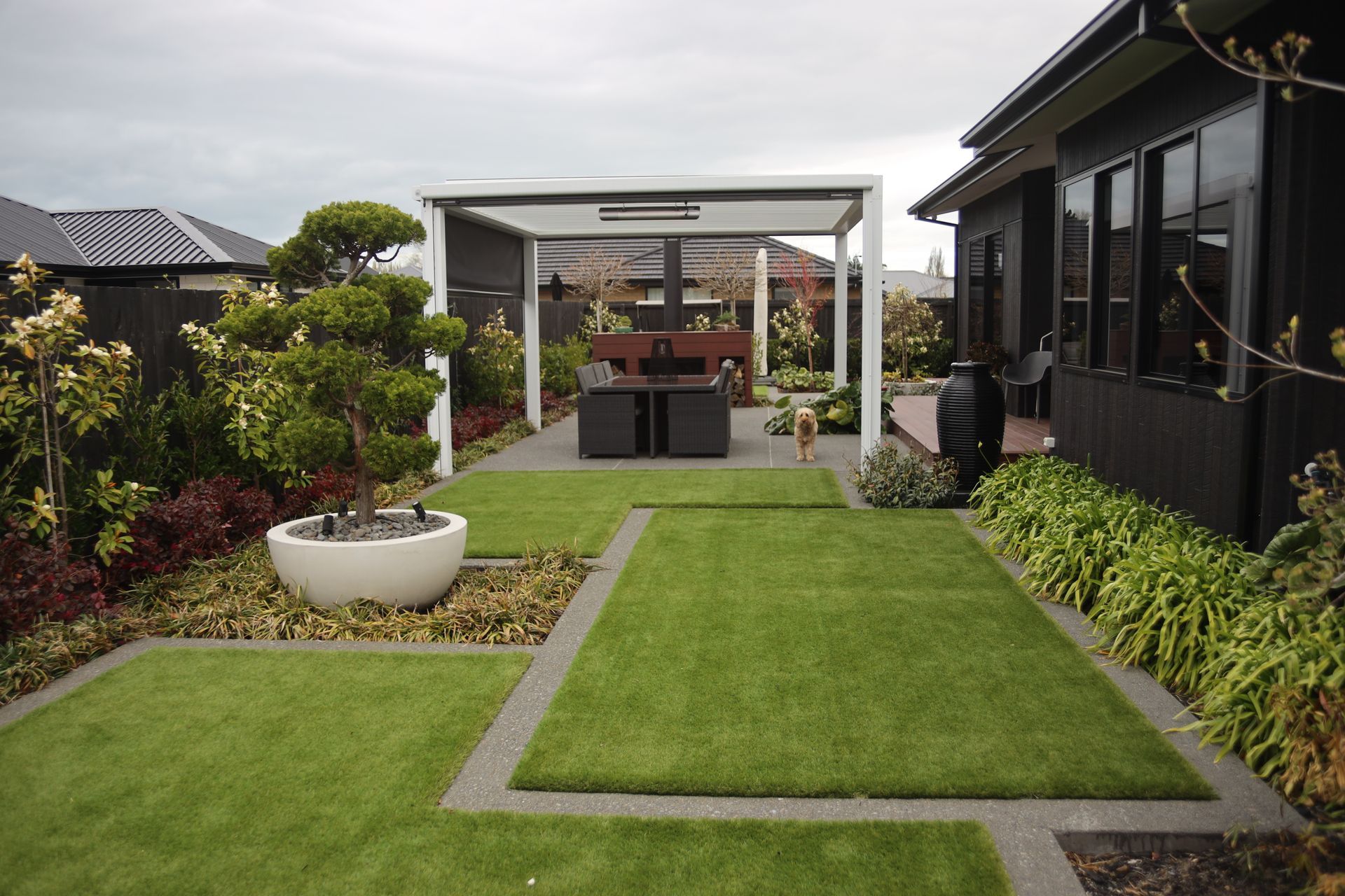 A lush green backyard with a pergola and a table