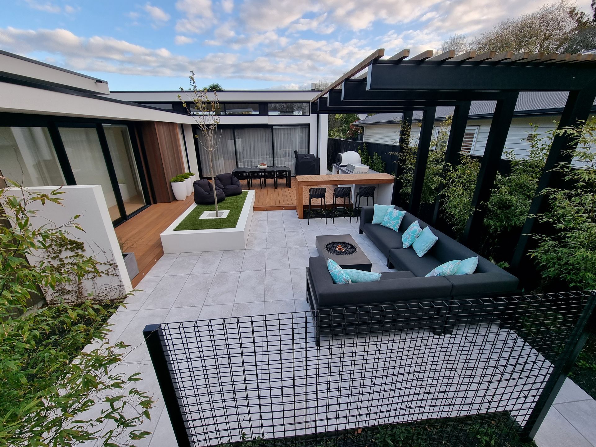 A patio with a couch , table , chairs and a pergola.