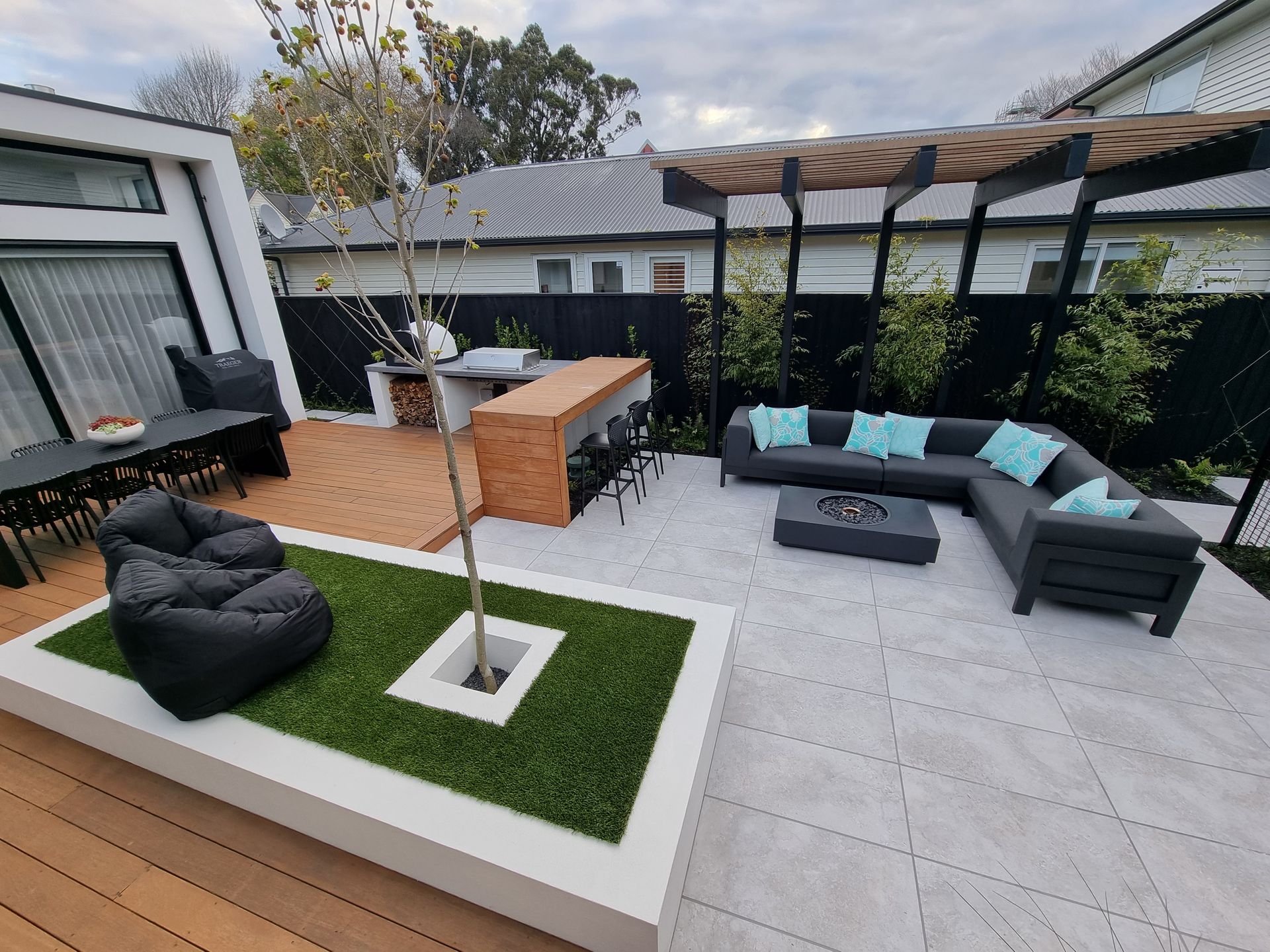 A patio with a couch , chair , table and a tree in the middle.