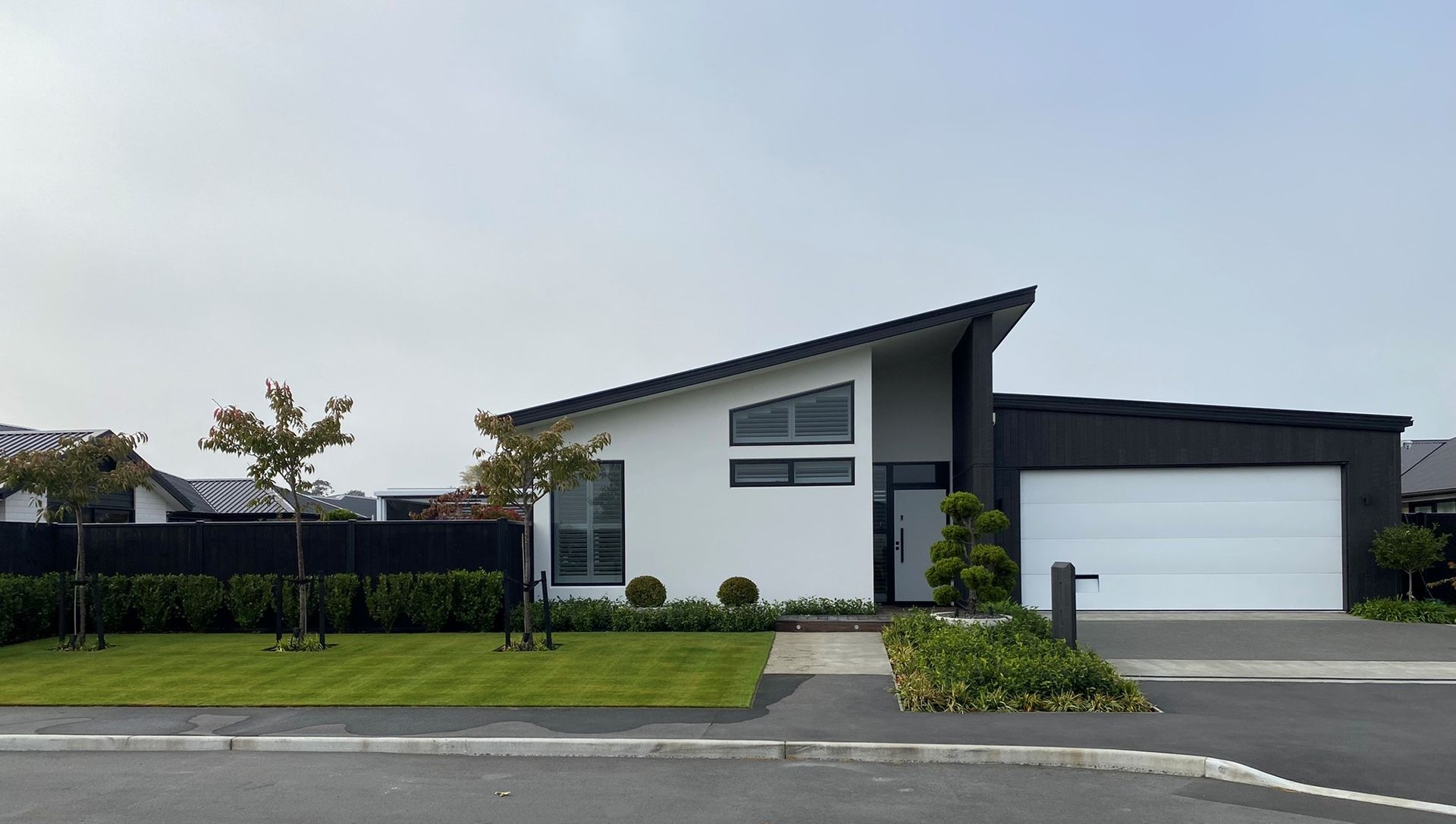 A white house with a black roof and a white garage door