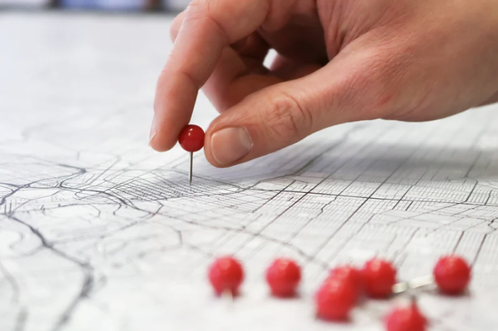 A person is pinning a red pin on a map.