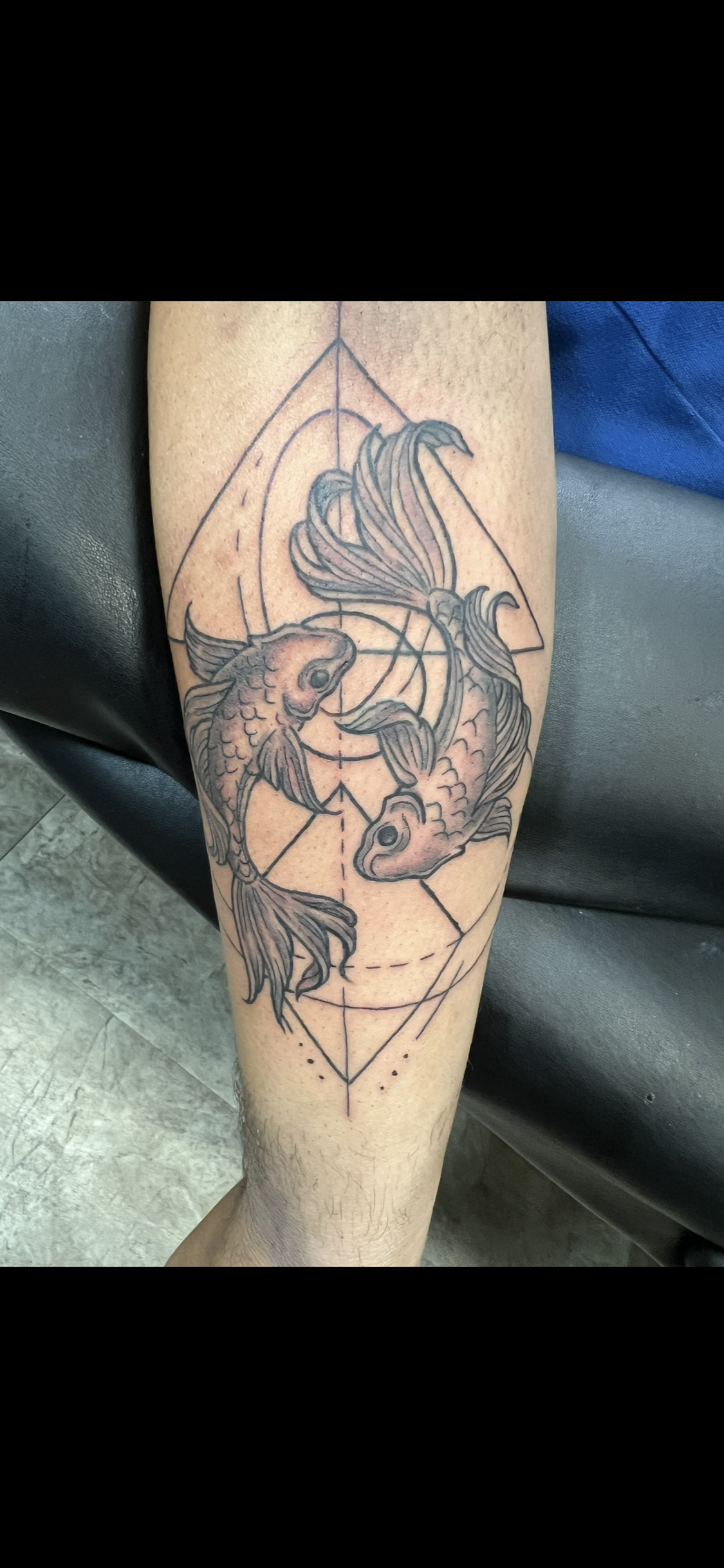 Tattoo of two koi fish in a geometric design on an arm.
