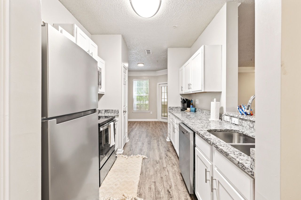 Modern apartment kitchen with stainless steel appliances and granite countertops.
