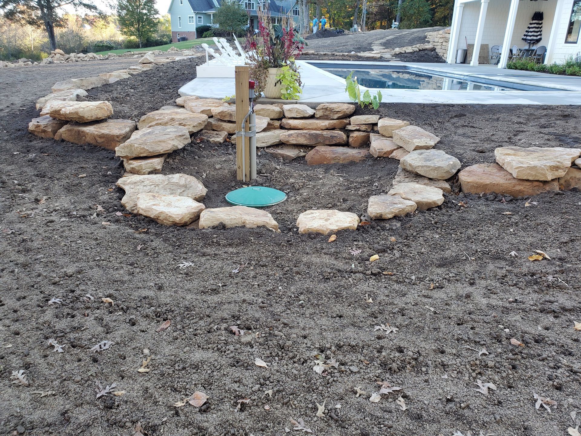 A circle of rocks in a yard next to a pool.