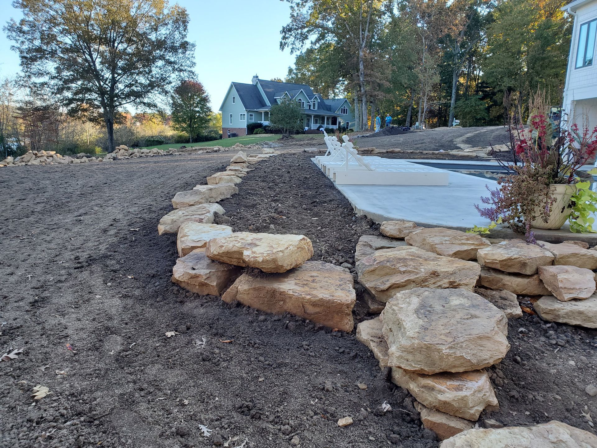 A pile of rocks sitting on top of a dirt field in front of a house.