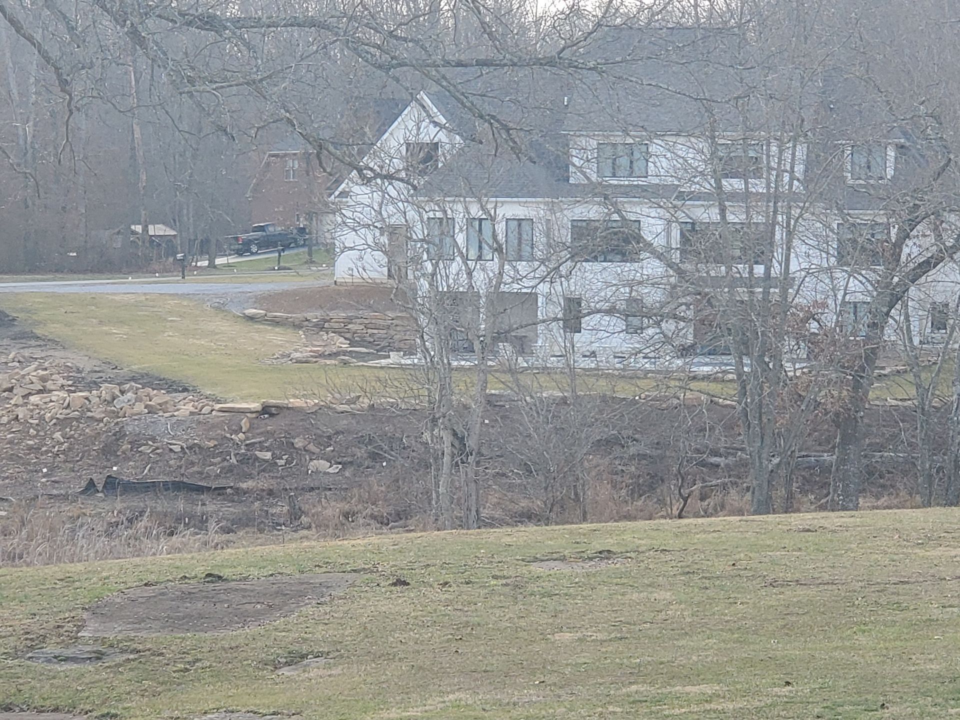 A large white house is sitting in the middle of a grassy field.