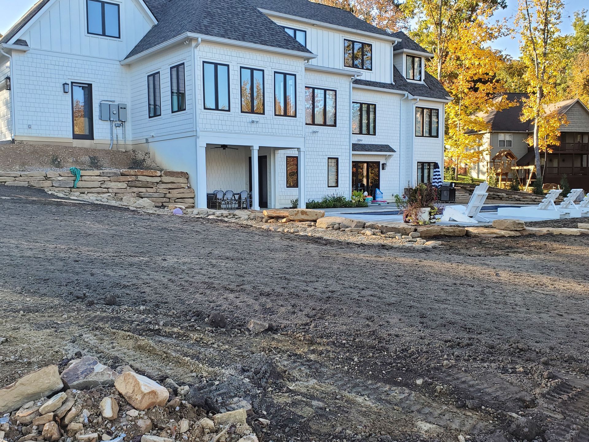 A large white house is sitting on top of a dirt field.
