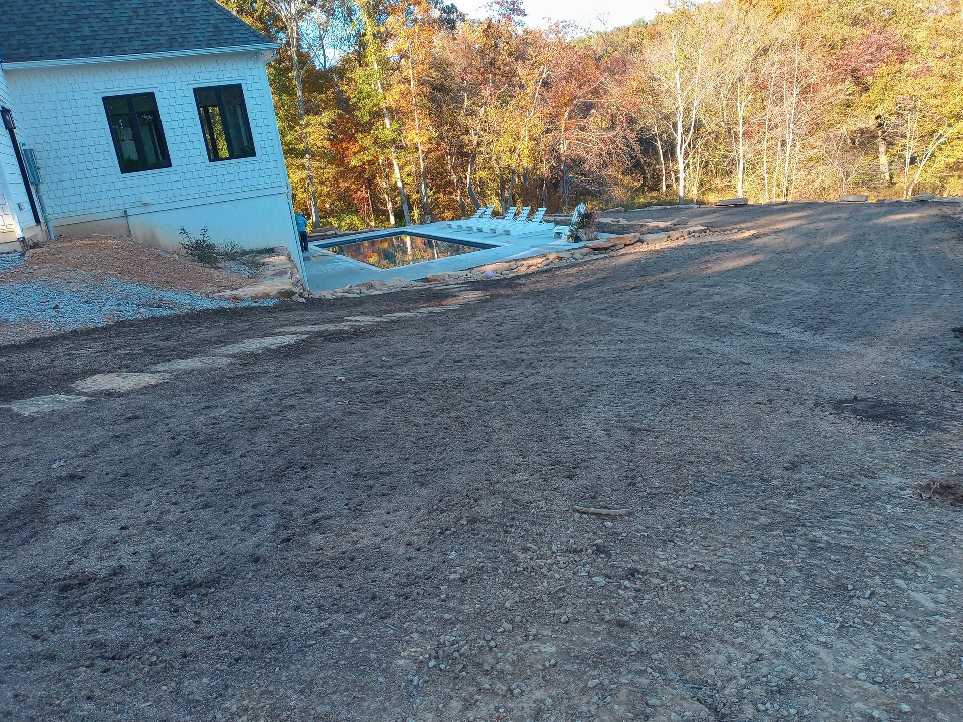 A white house is sitting on top of a dirt hill.