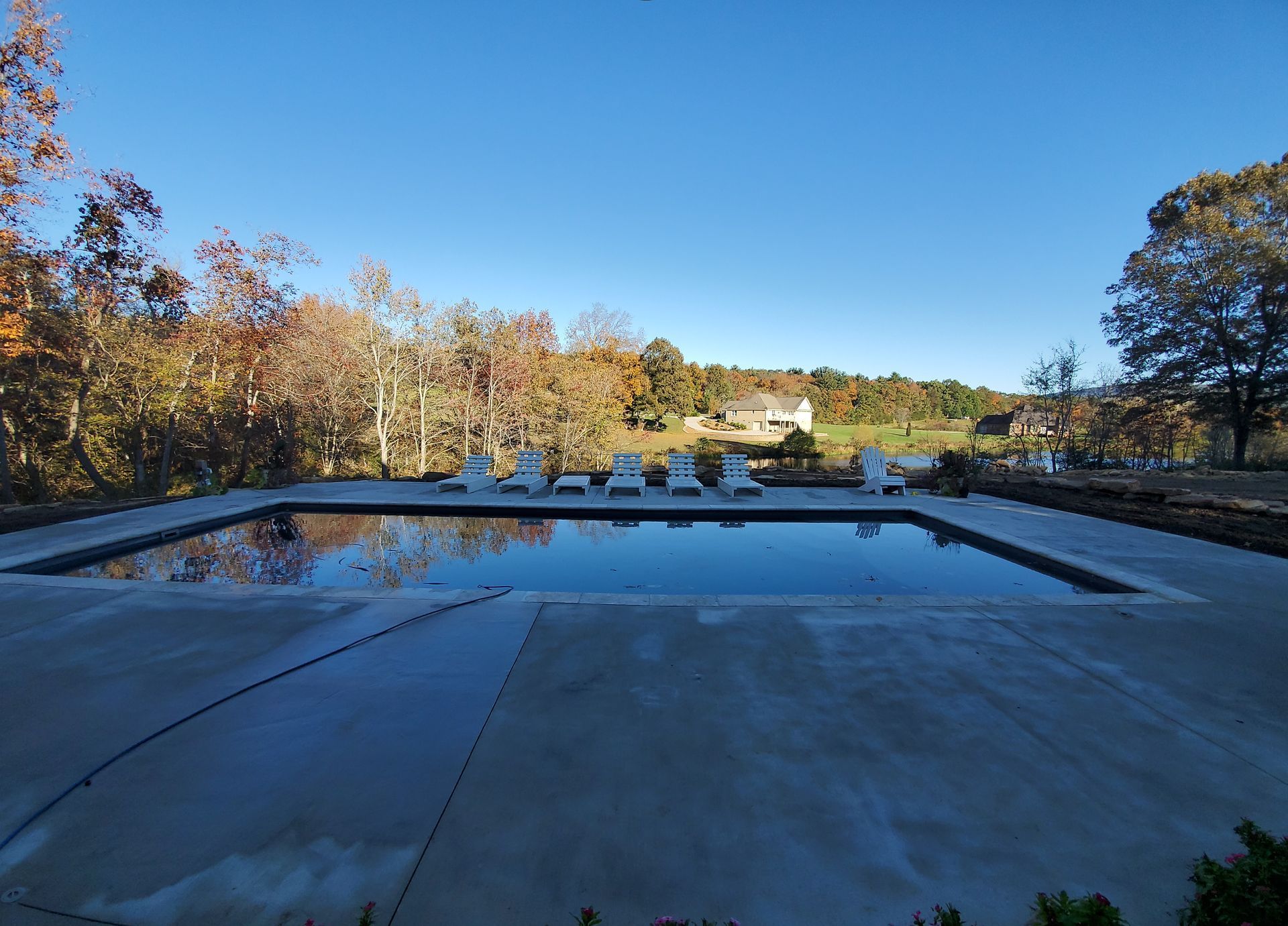 A large swimming pool with chairs around it on a sunny day.