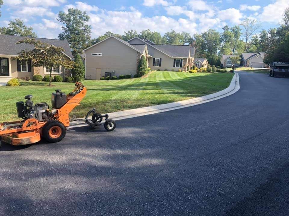 A lawn mower is parked on the side of the road in front of a house.