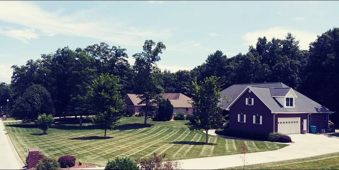 A house is sitting on top of a lush green field surrounded by trees.