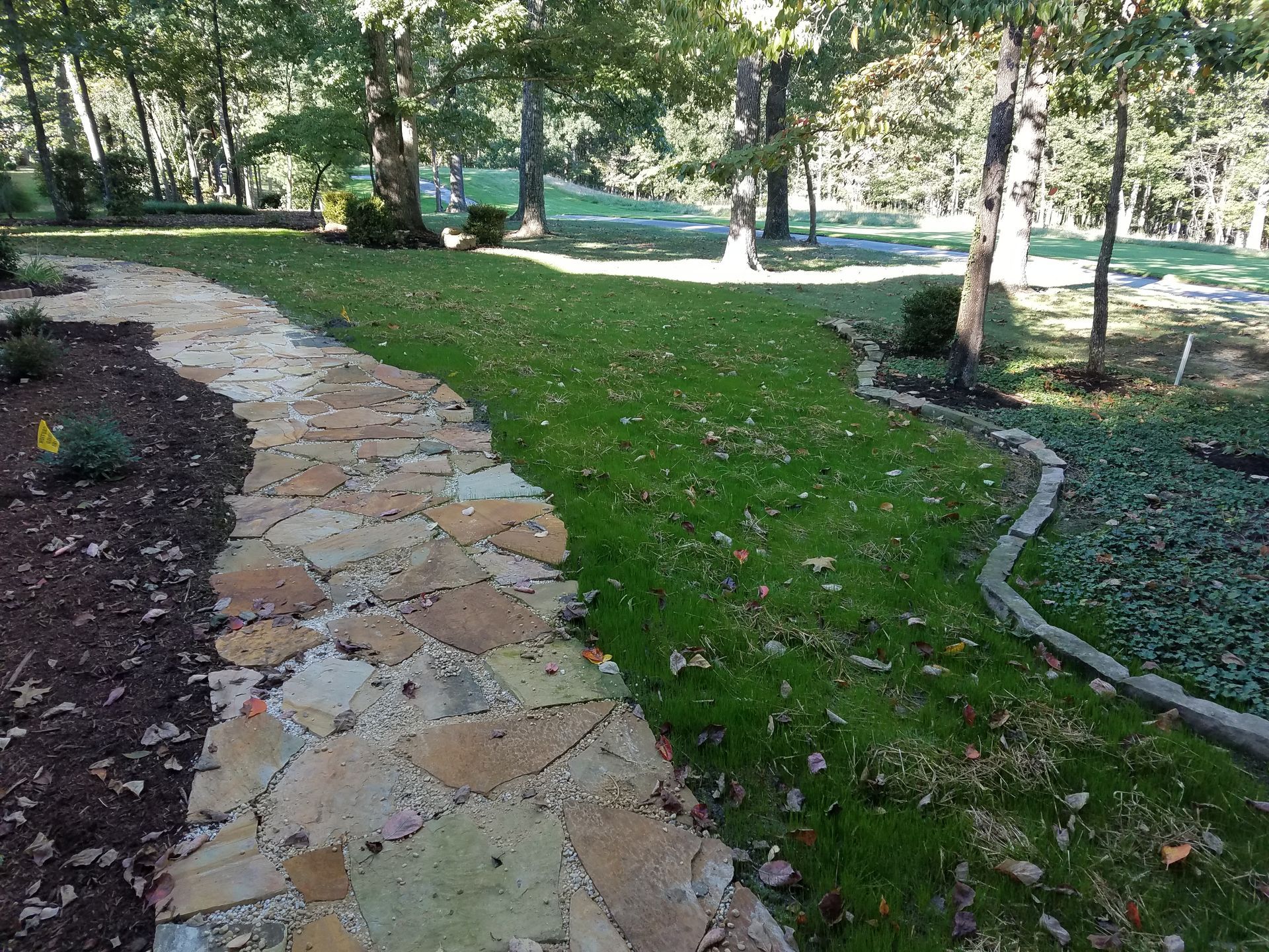 A stone walkway going through a lush green field.
