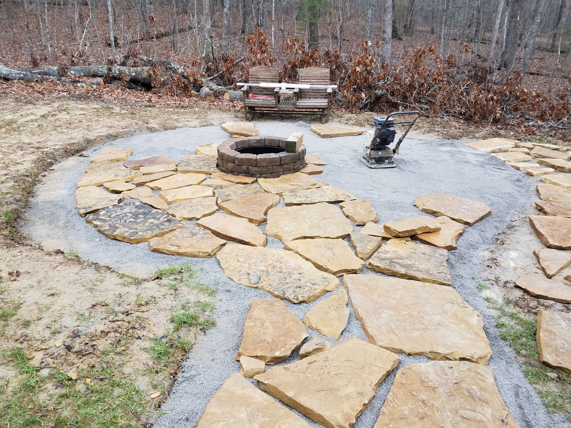 A fire pit is surrounded by rocks in the middle of a yard.