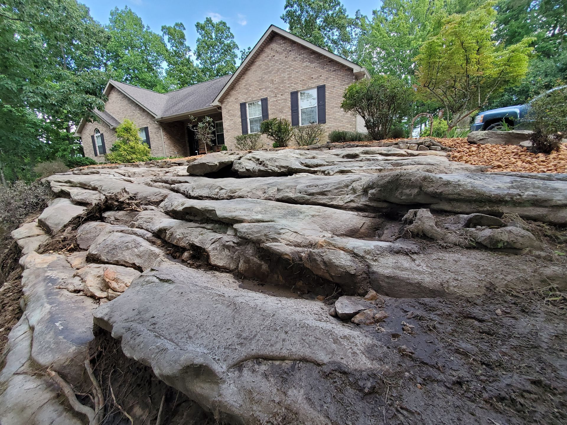 There is a large rock in front of a house.