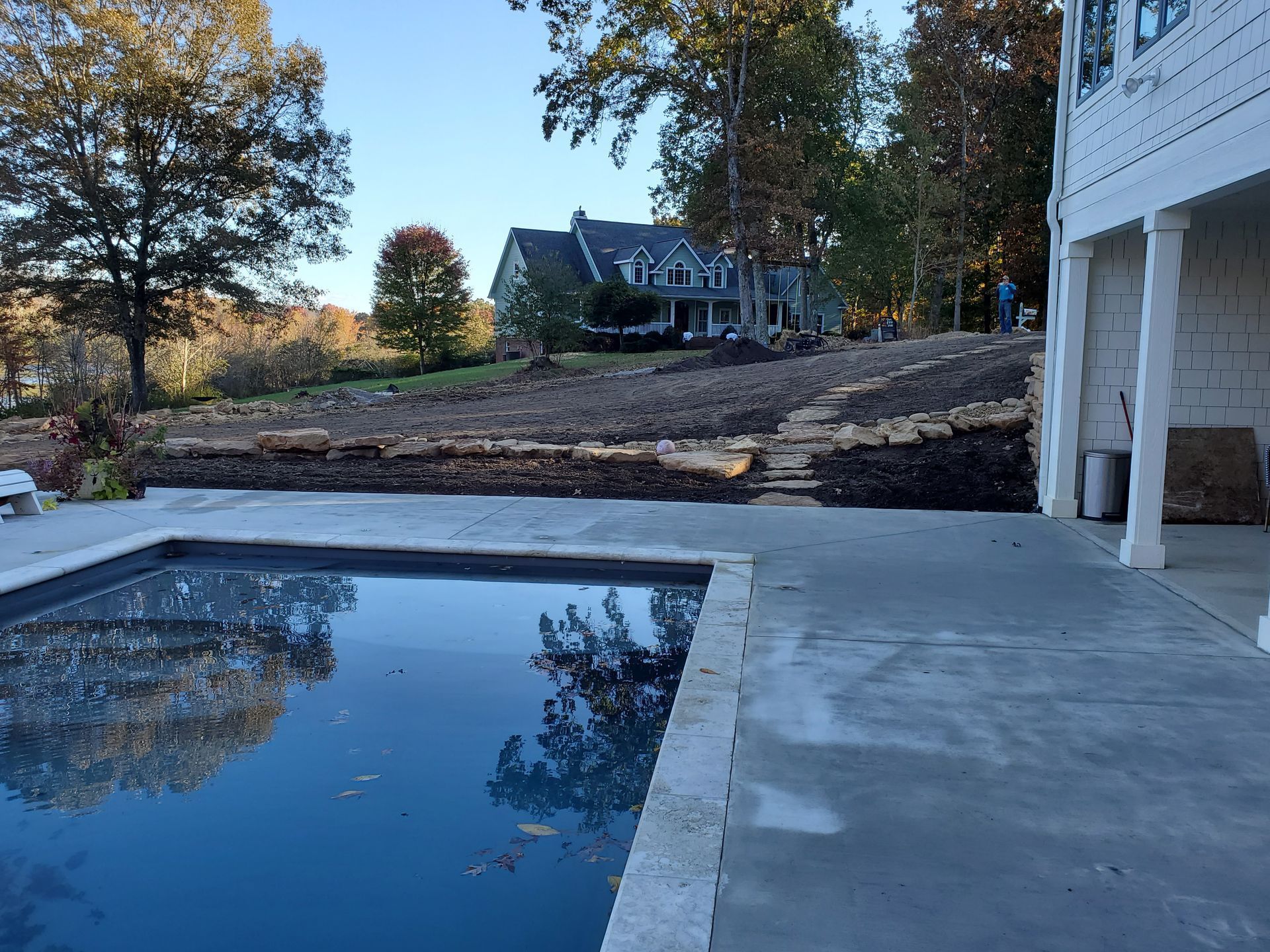 A large swimming pool is in the backyard of a house.