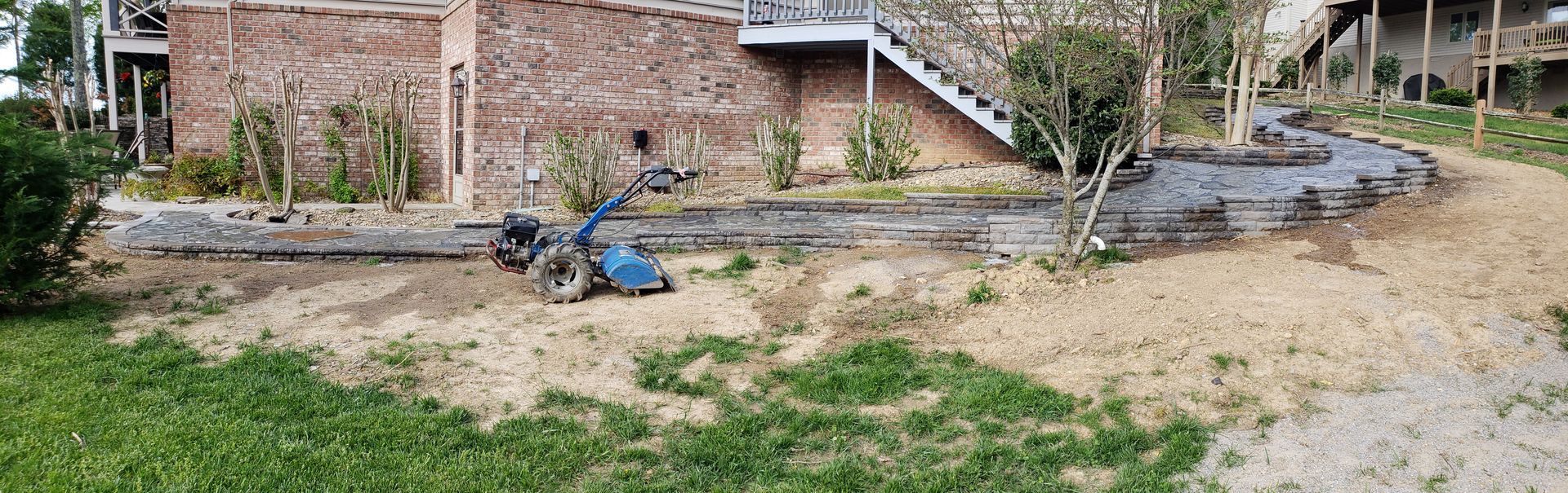 A person is using a lawn mower to cut the grass in front of a house.