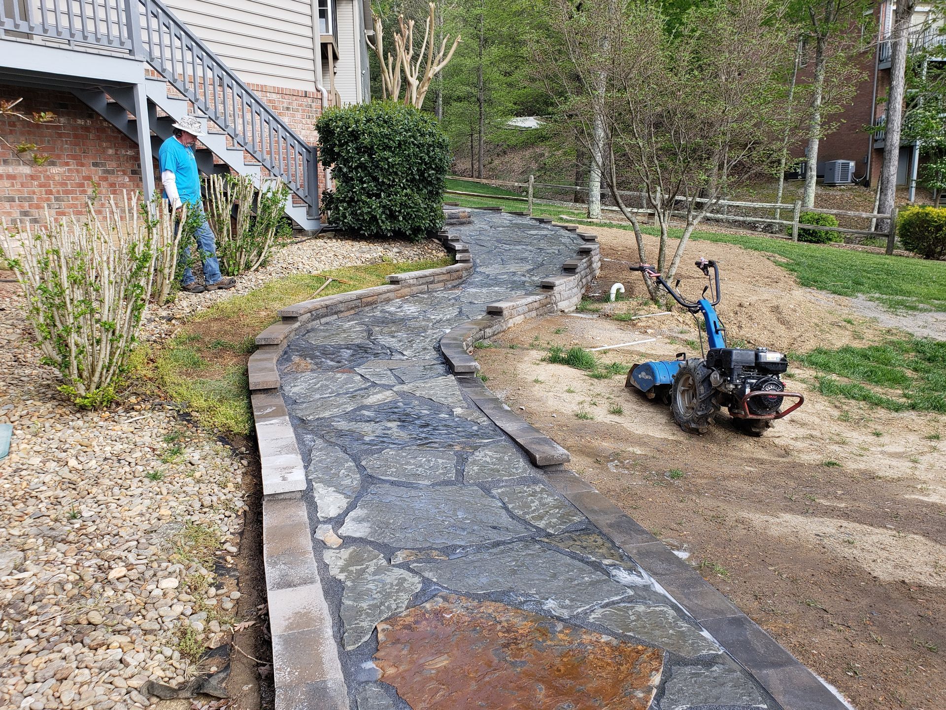 A stone walkway is being built in the backyard of a house.