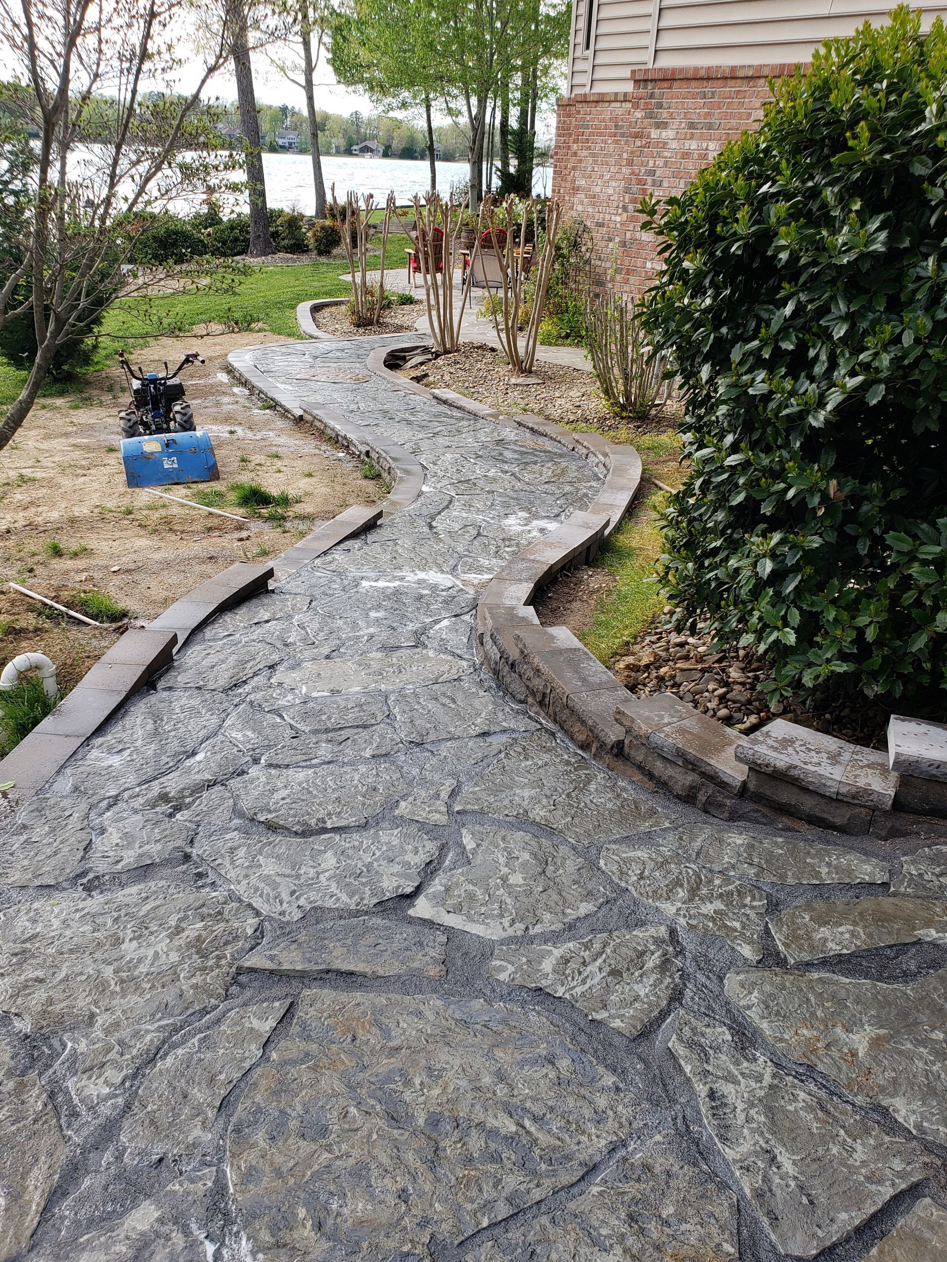 A stone walkway is being built in the backyard of a house.