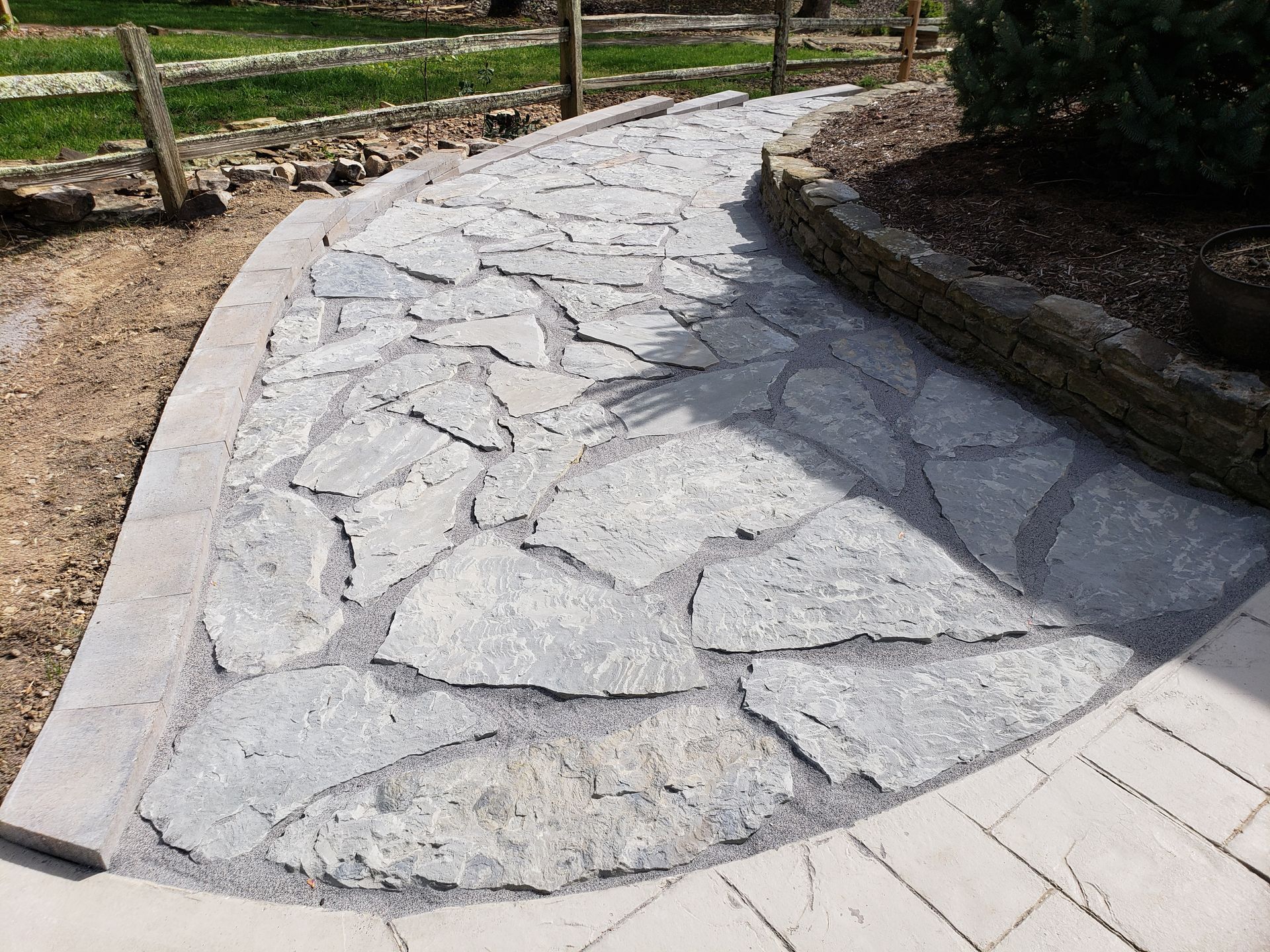 A stone walkway with a fence in the background.