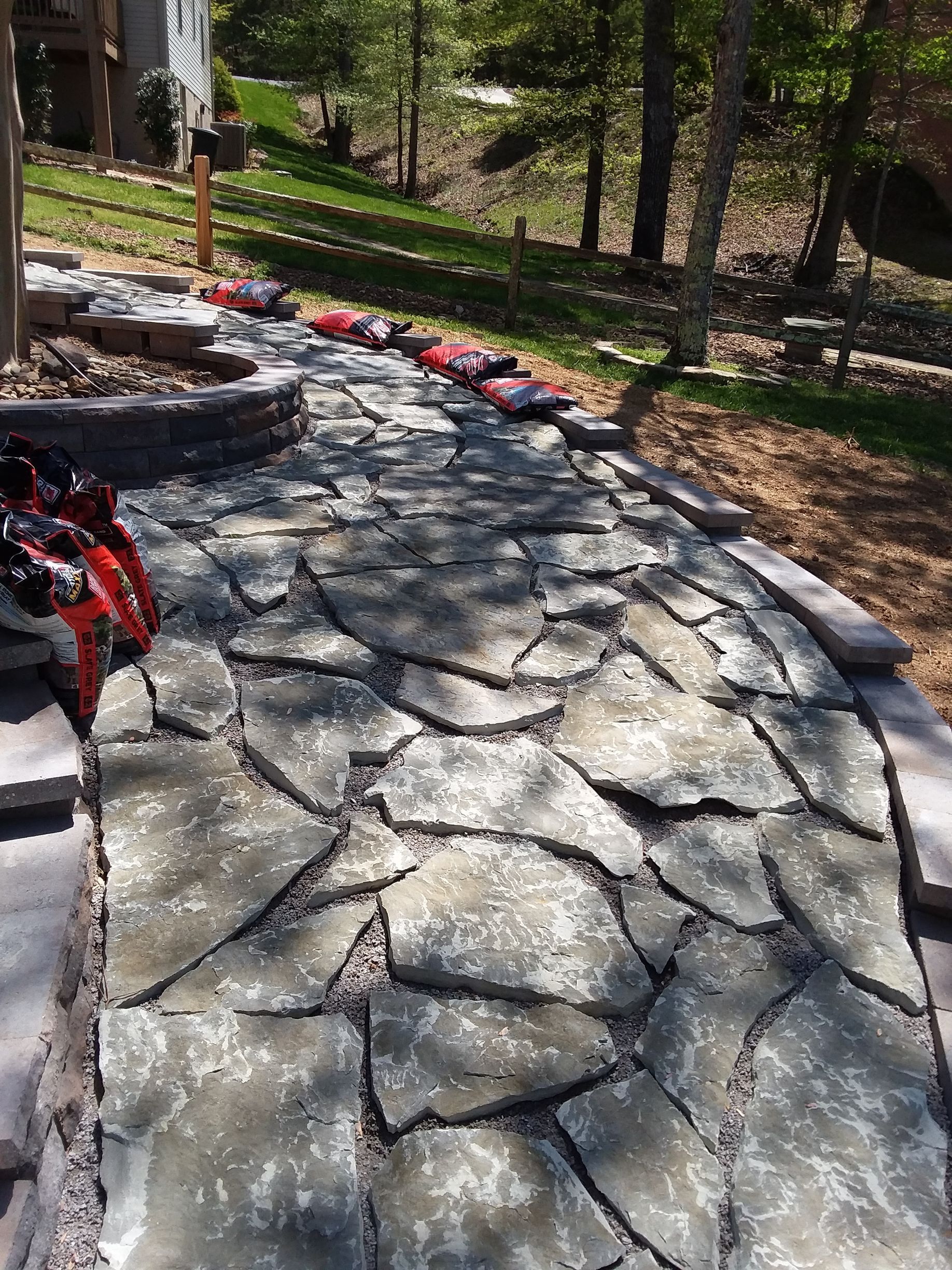 A stone walkway is being built in a backyard.