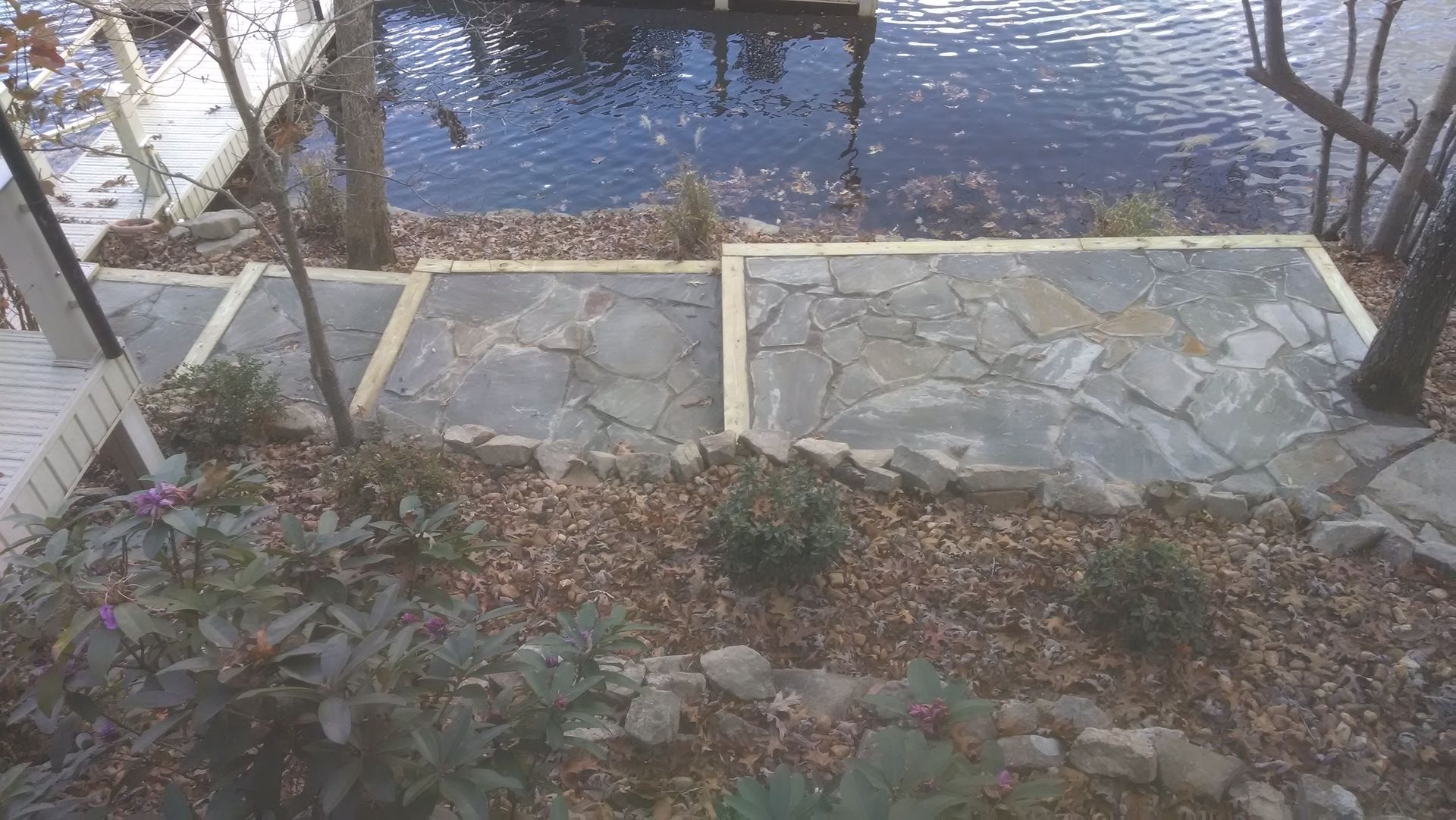 A stone walkway leading to a dock next to a body of water.