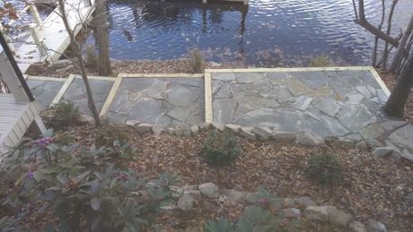 A stone walkway leading to a dock next to a body of water.