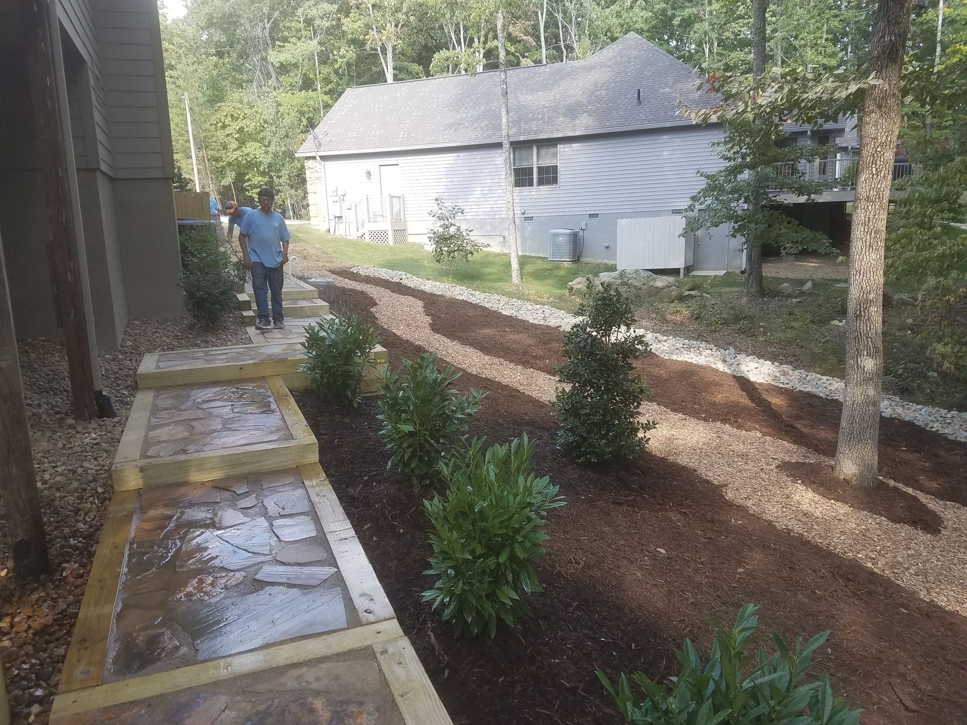 A man is walking down a path in front of a house.