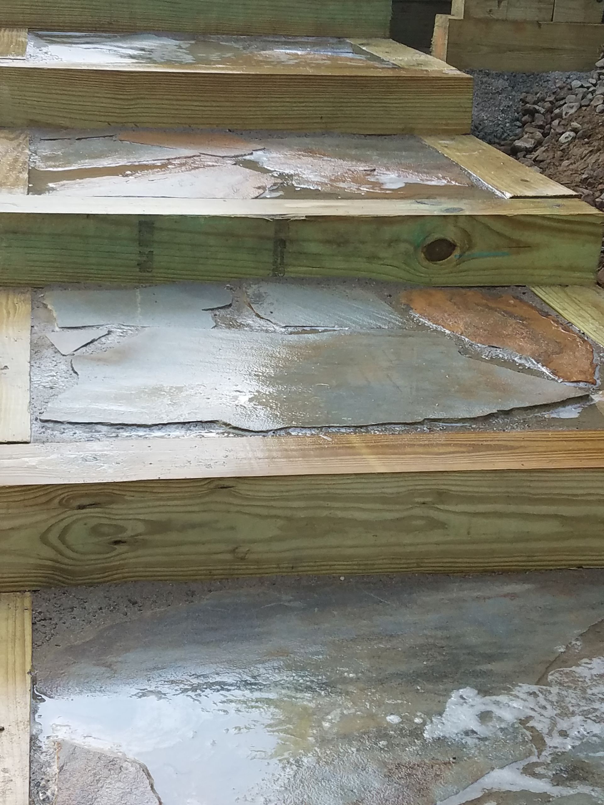 A close up of a wooden staircase with concrete steps.