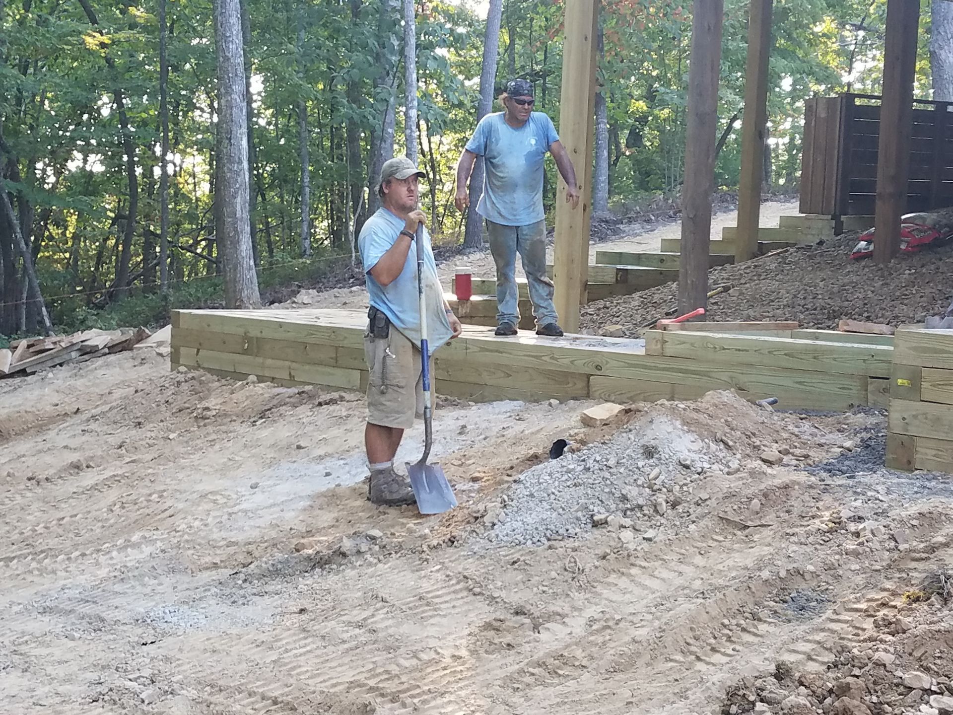 Two men are working on a wooden structure in the yard.