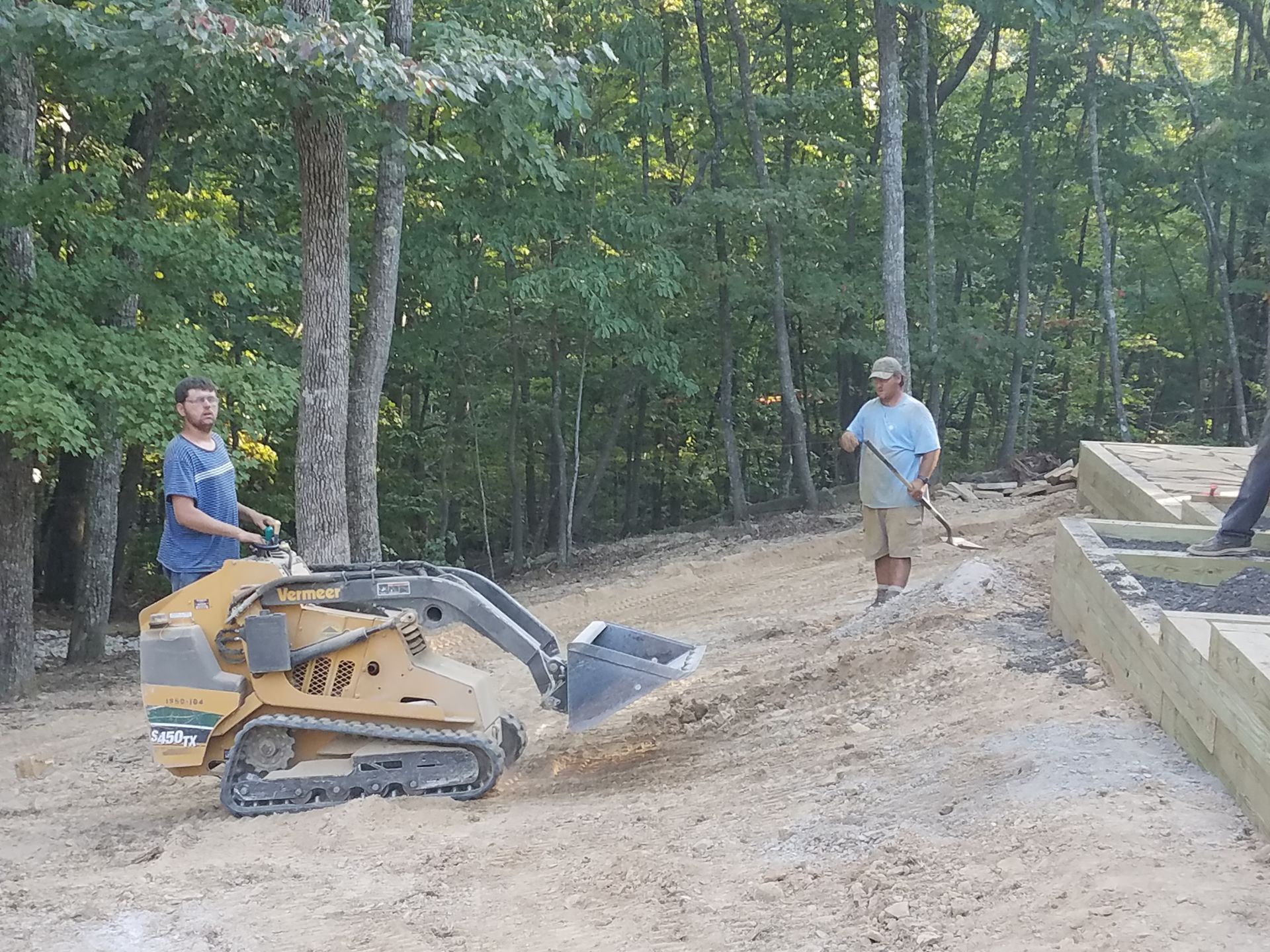 Two men are on a tractor working on a lawn project.