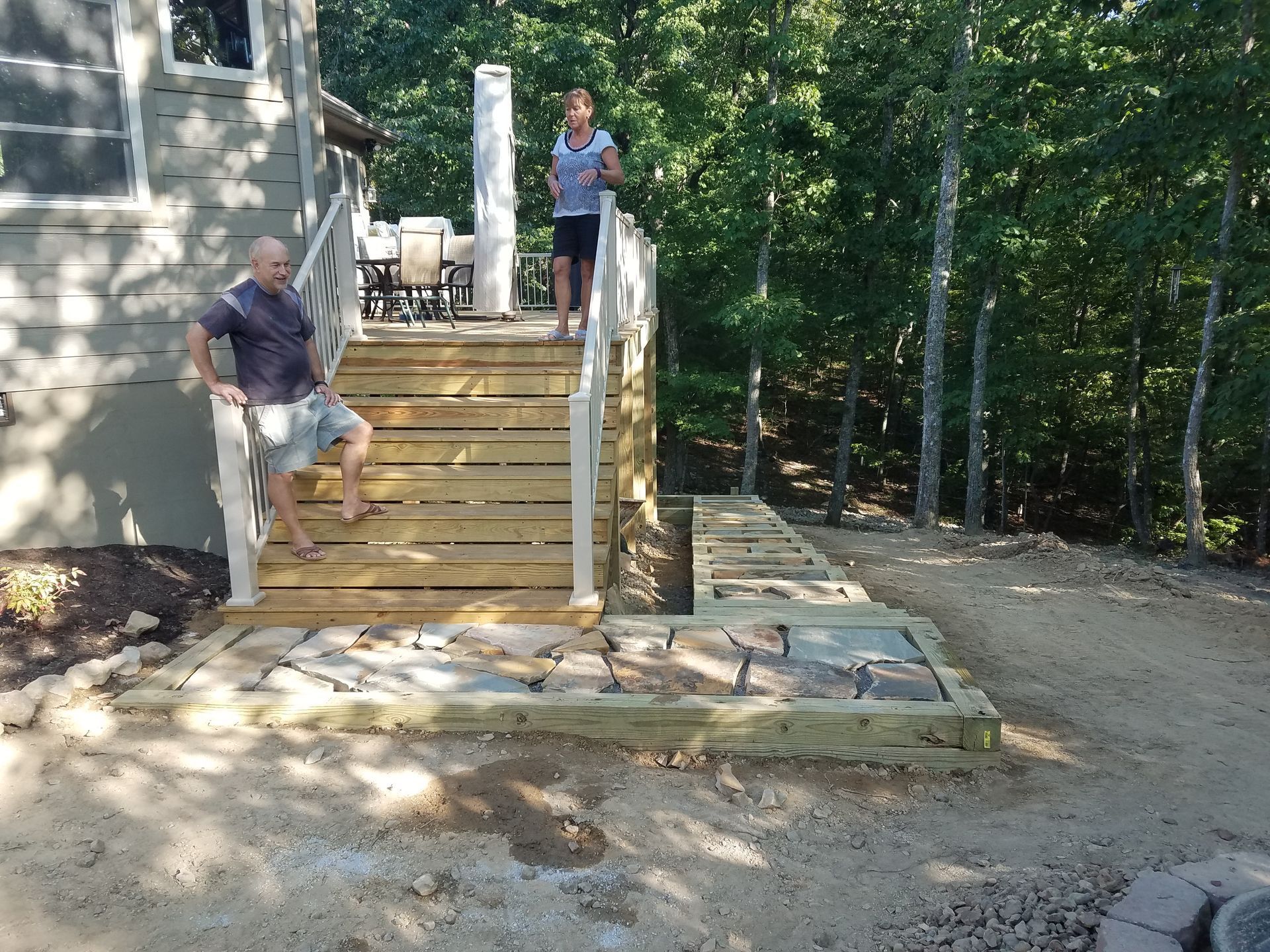 A man and a woman are standing on a wooden deck