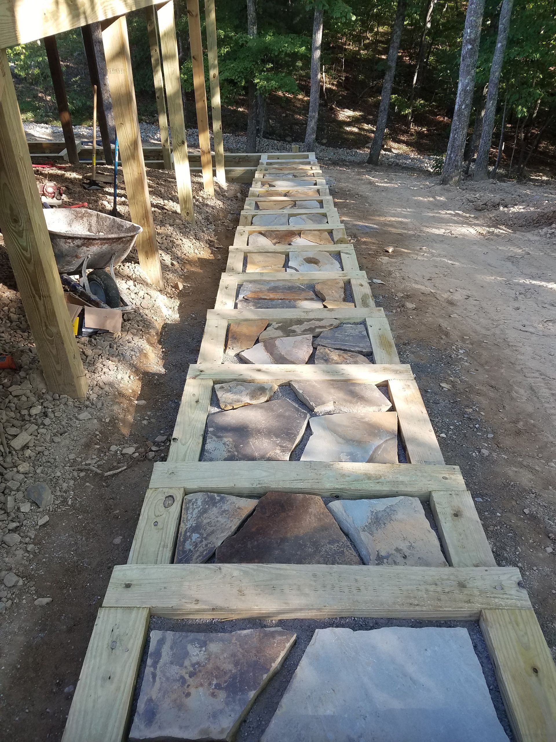 A wooden walkway made of stone and wood is being built in the woods.