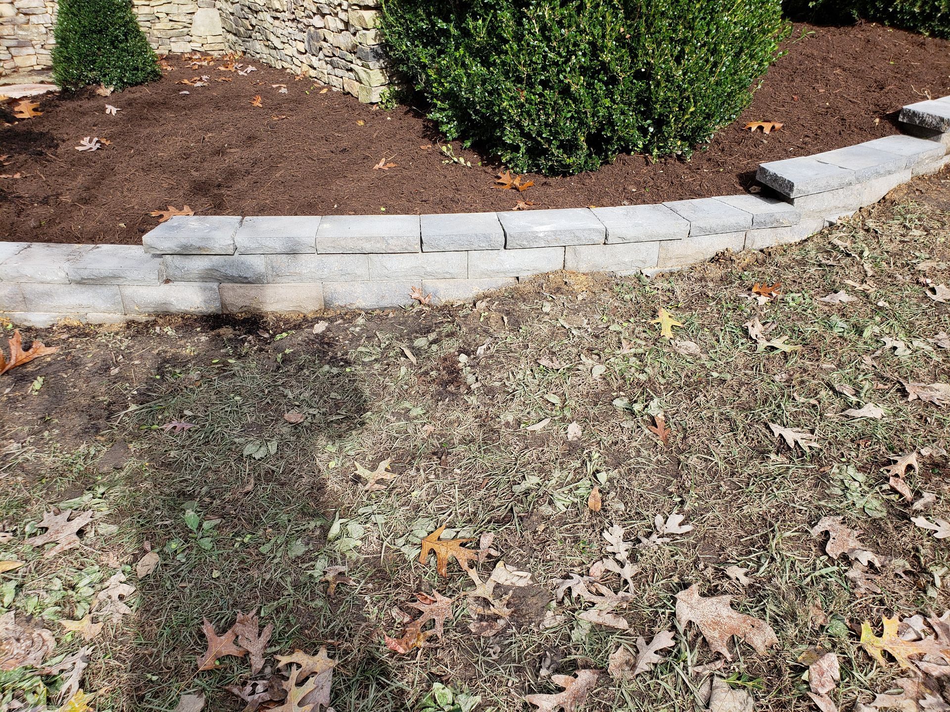 There is a brick wall in the middle of the grass.