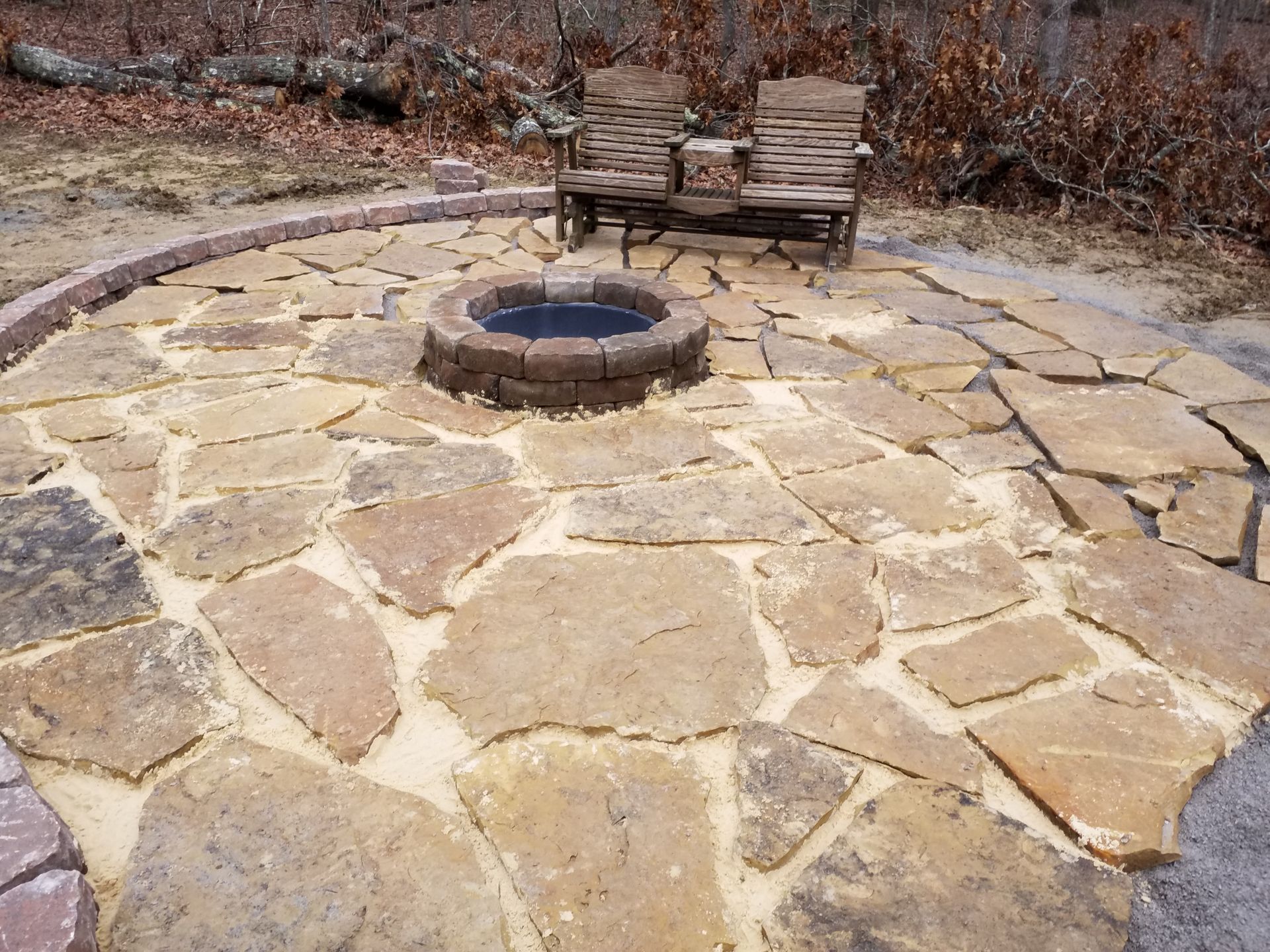 There is a fire pit in the middle of a stone patio.
