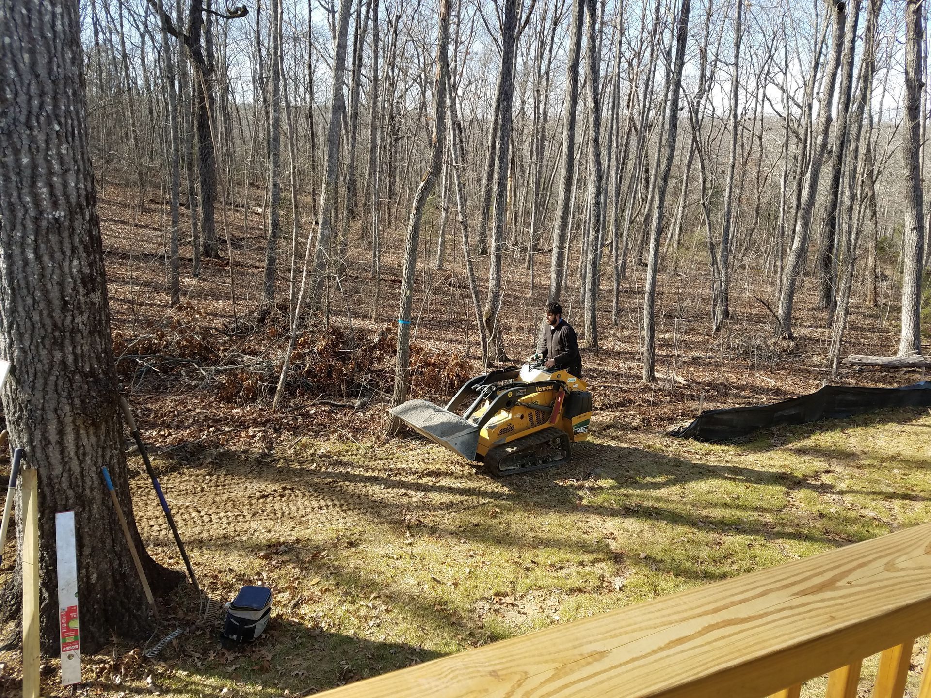 A man is riding a lawn mower in the woods.