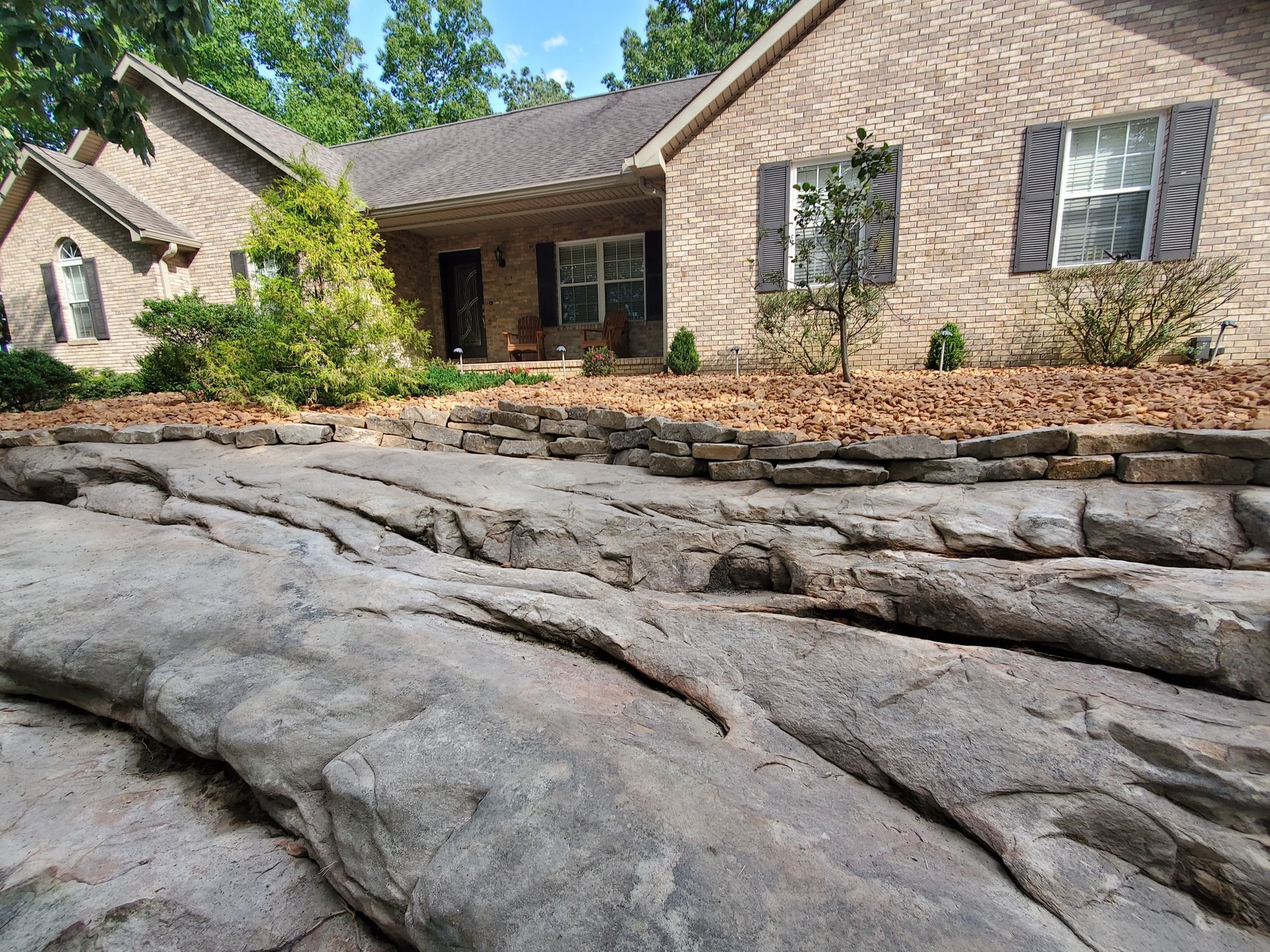 A brick house with a large rock in front of it