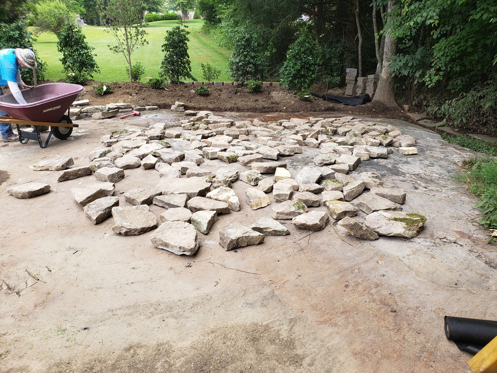 A man is pushing a wheelbarrow full of rocks.