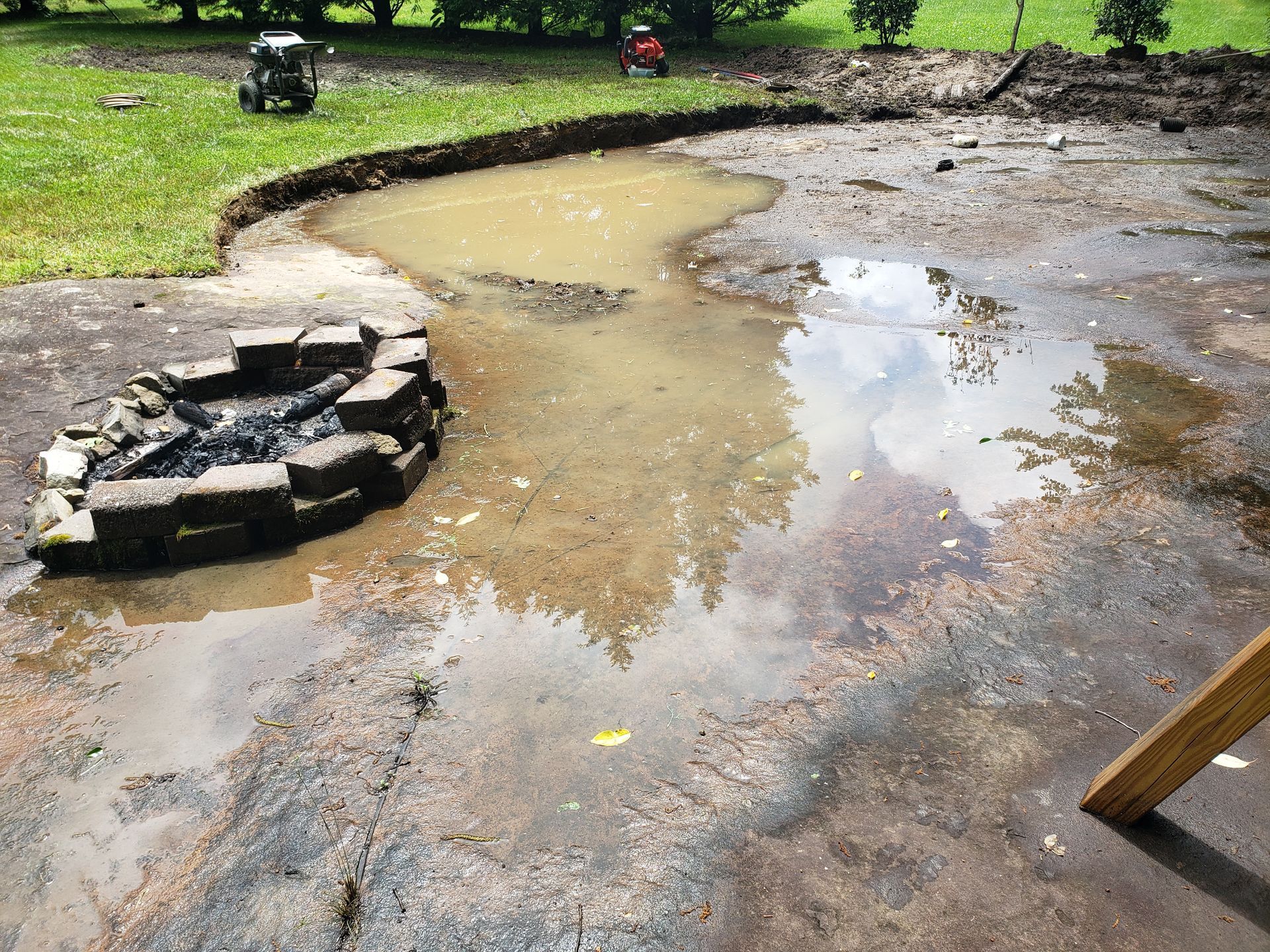 A muddy patio with a fire pit in the middle of it.