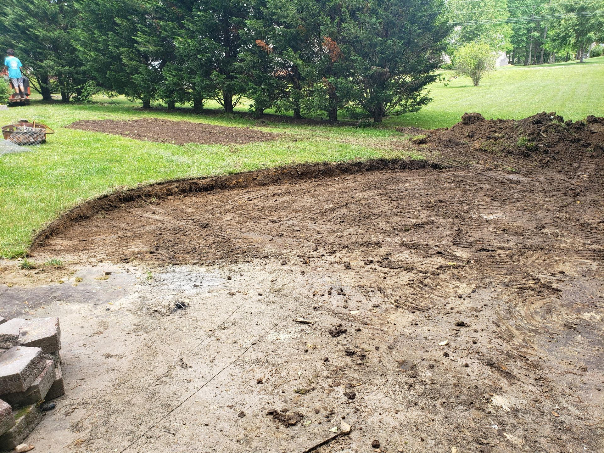 A large pile of dirt is sitting in the middle of a lush green field.