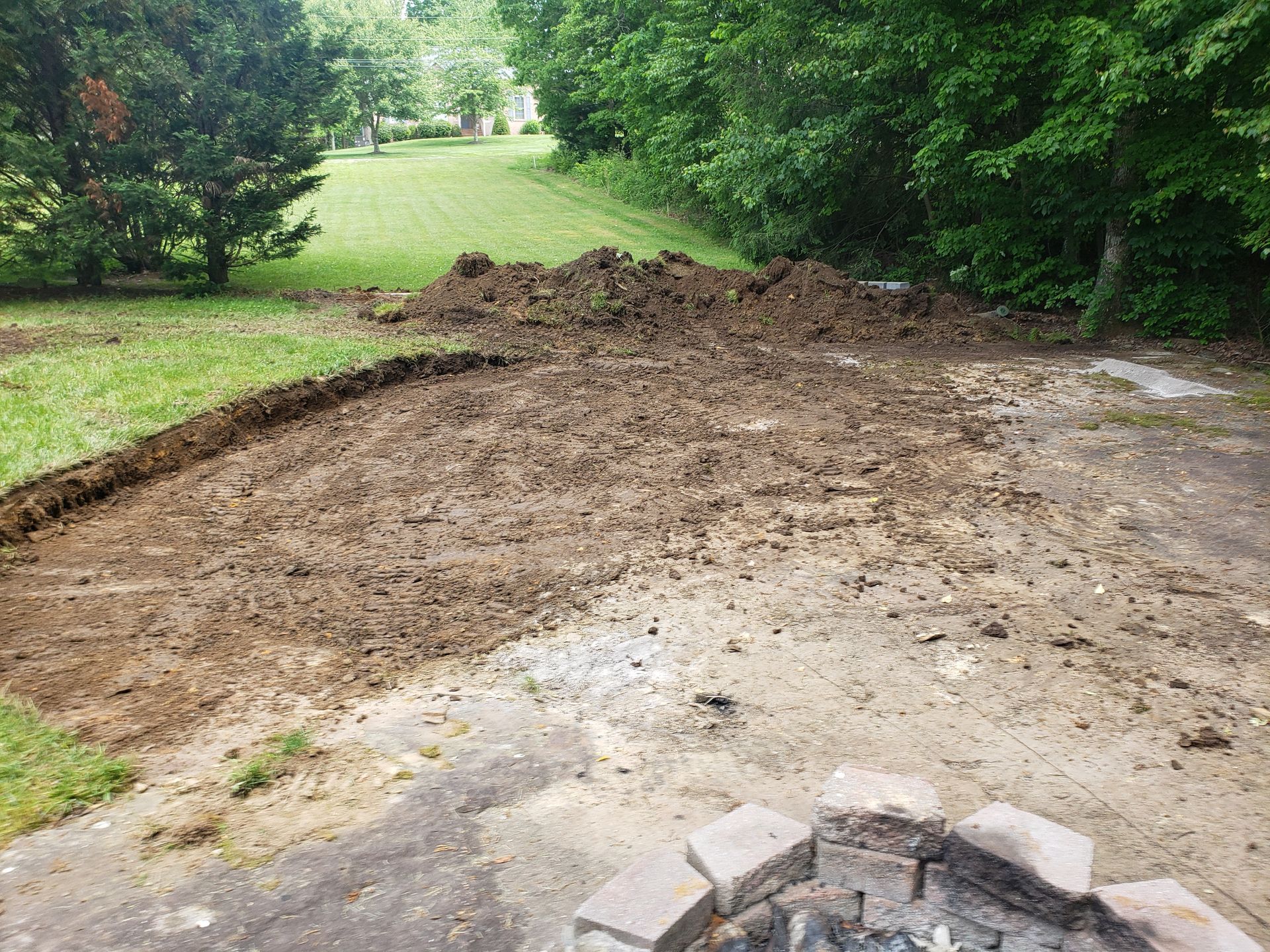 There is a fire pit in the middle of the dirt in the backyard.