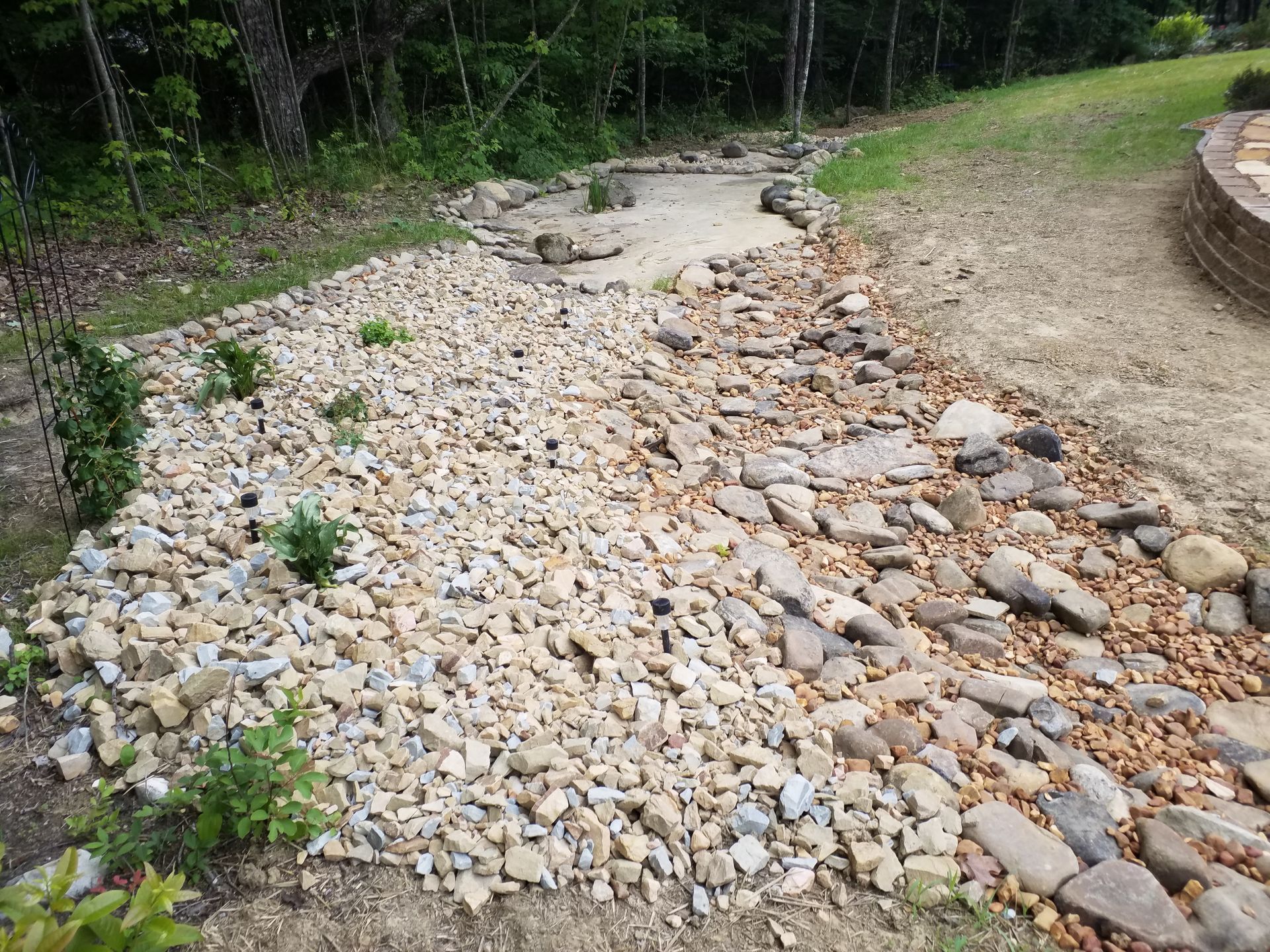A pile of rocks in a yard with trees in the background.