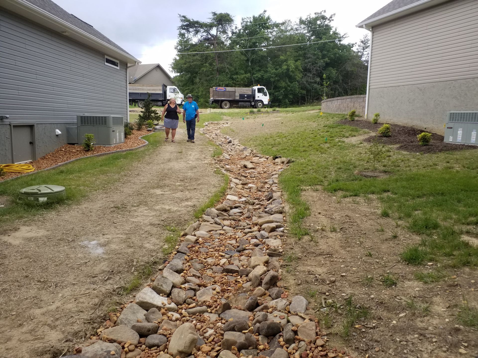 A couple walking down a dirt road next to a house