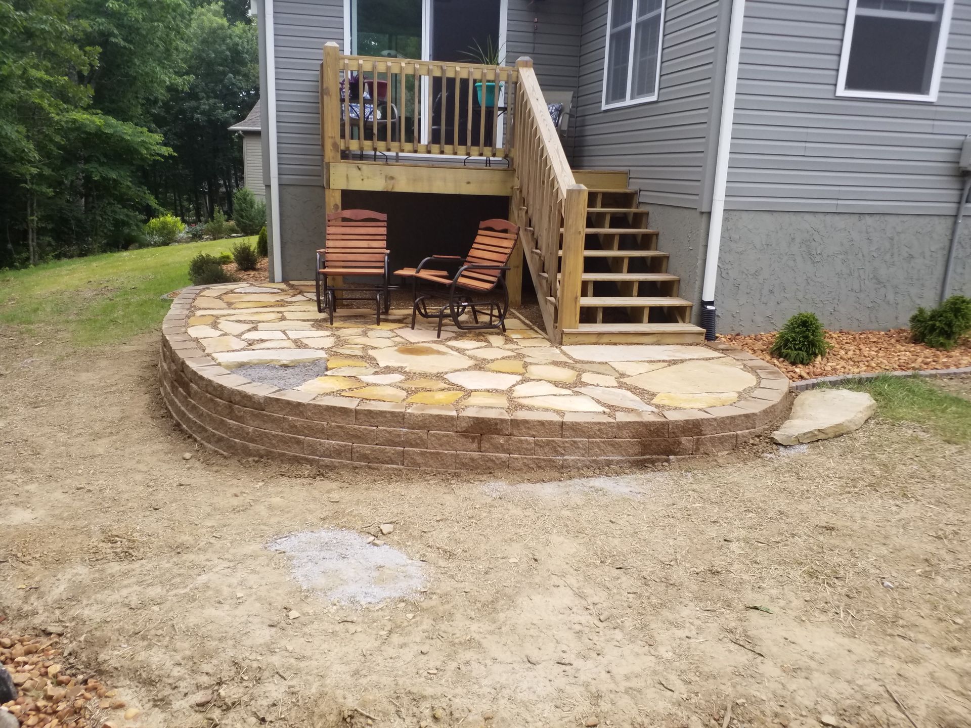 A patio with a deck and stairs in the backyard of a house.