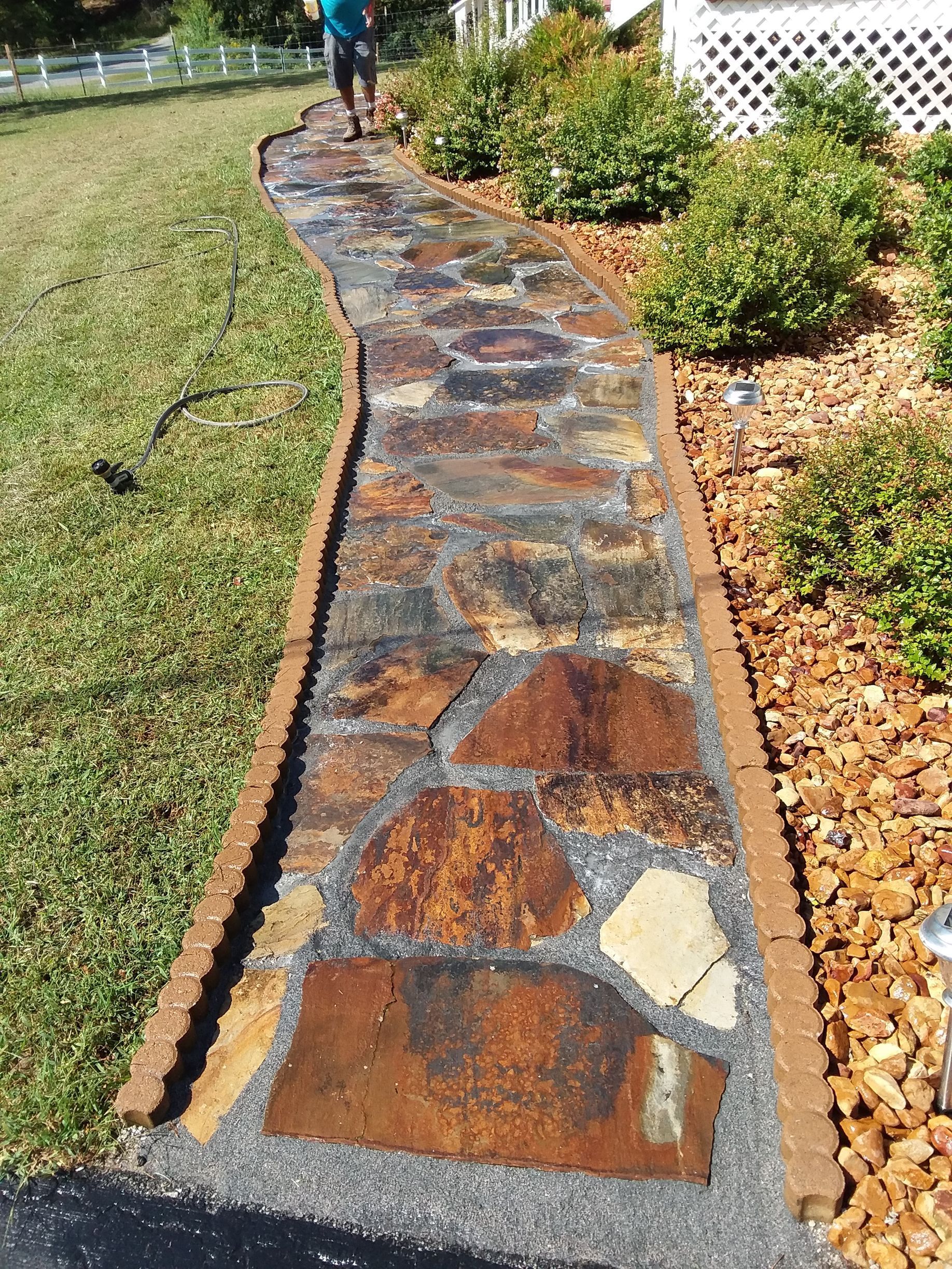 A man is walking down a stone walkway in a yard.