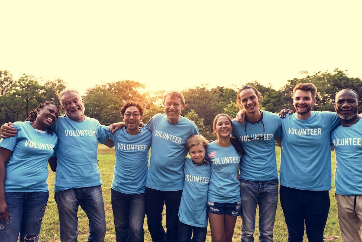 a group of volunteers are posing for a picture in a field .