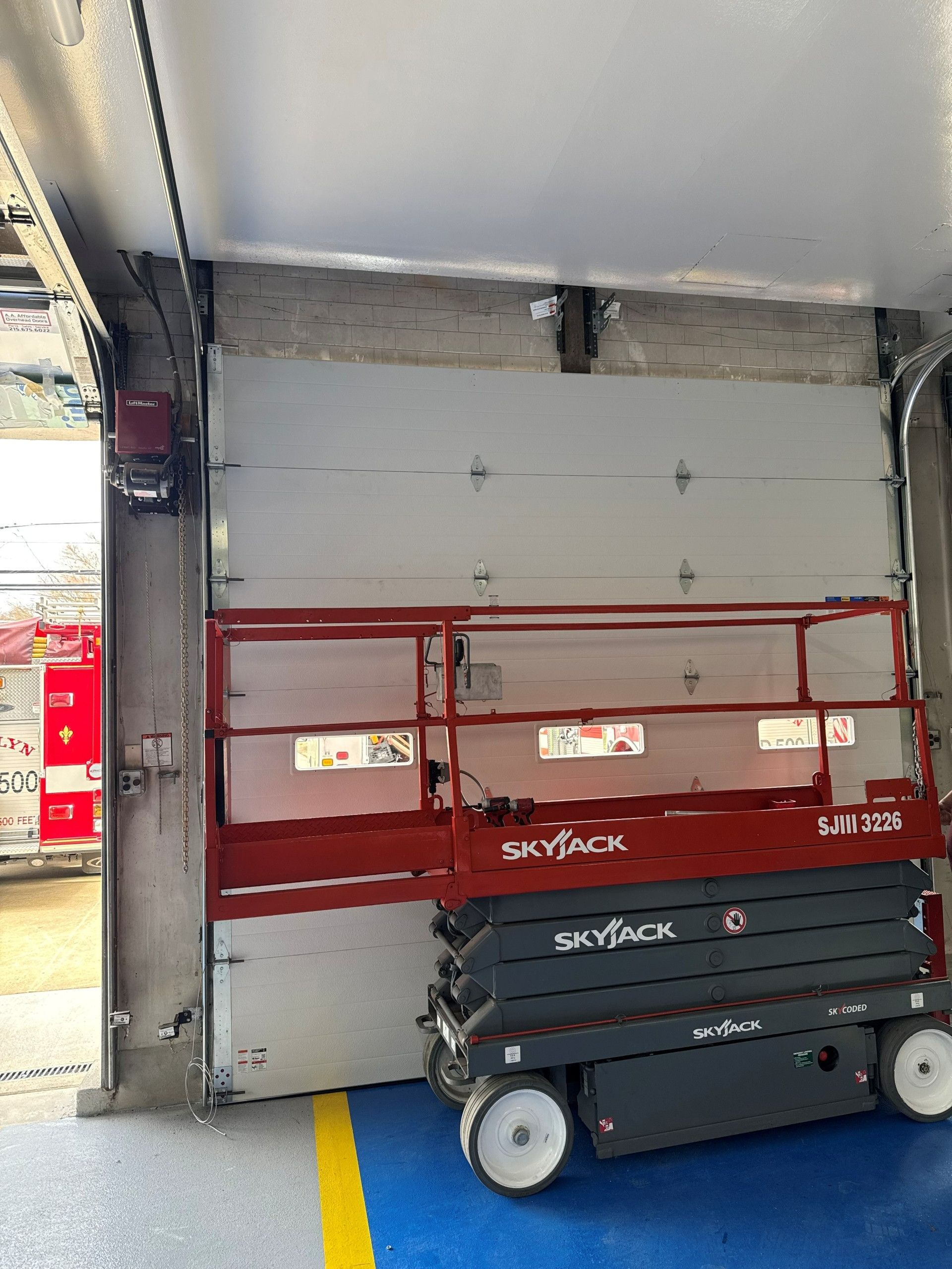 Two workers in orange hard hats and overalls installing a white garage door. Two workers in orange hard hats and overalls installing a white garage door.